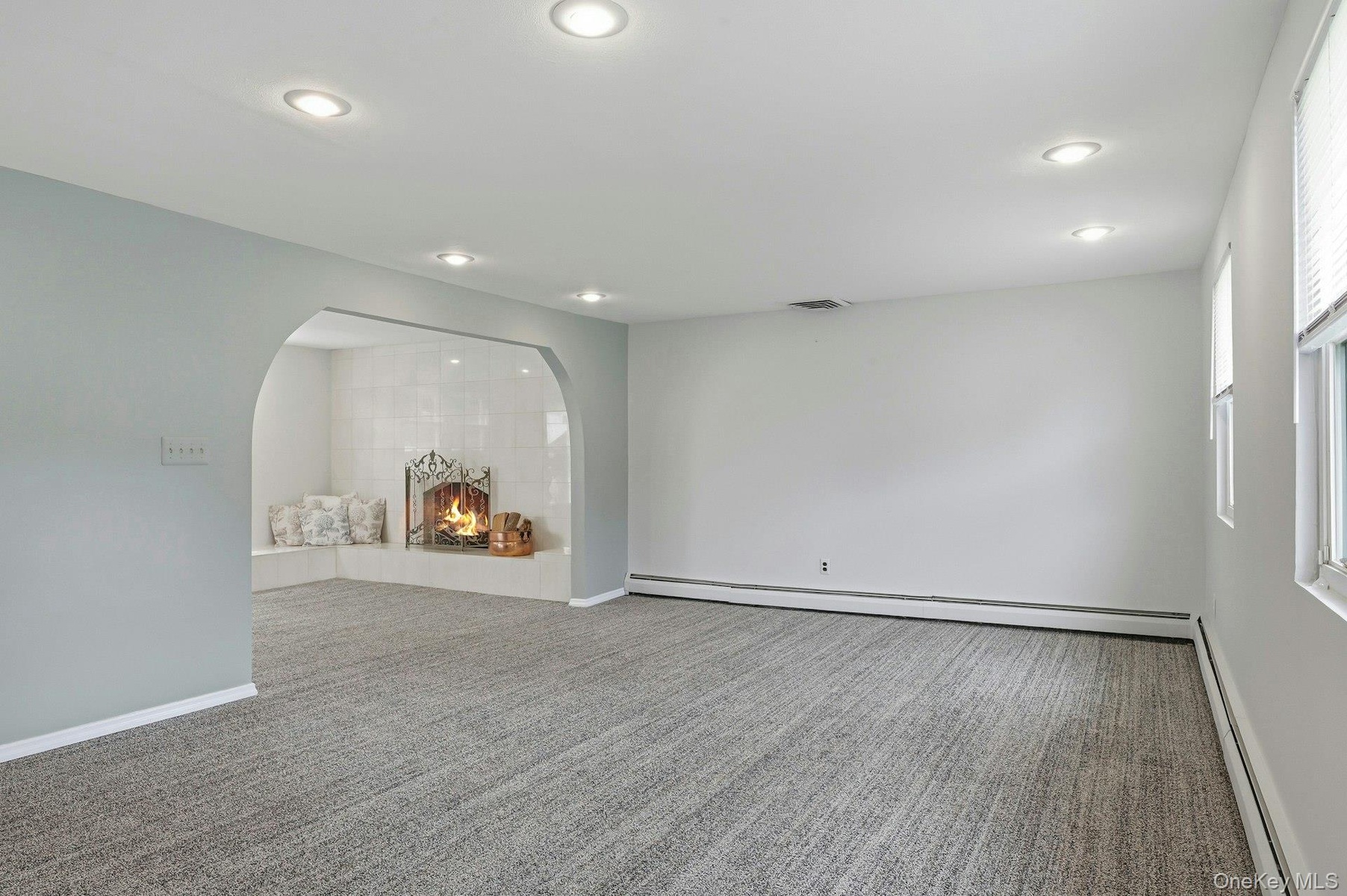 Spacious room featuring neutral carpeting, recessed lighting, and white baseboard trim