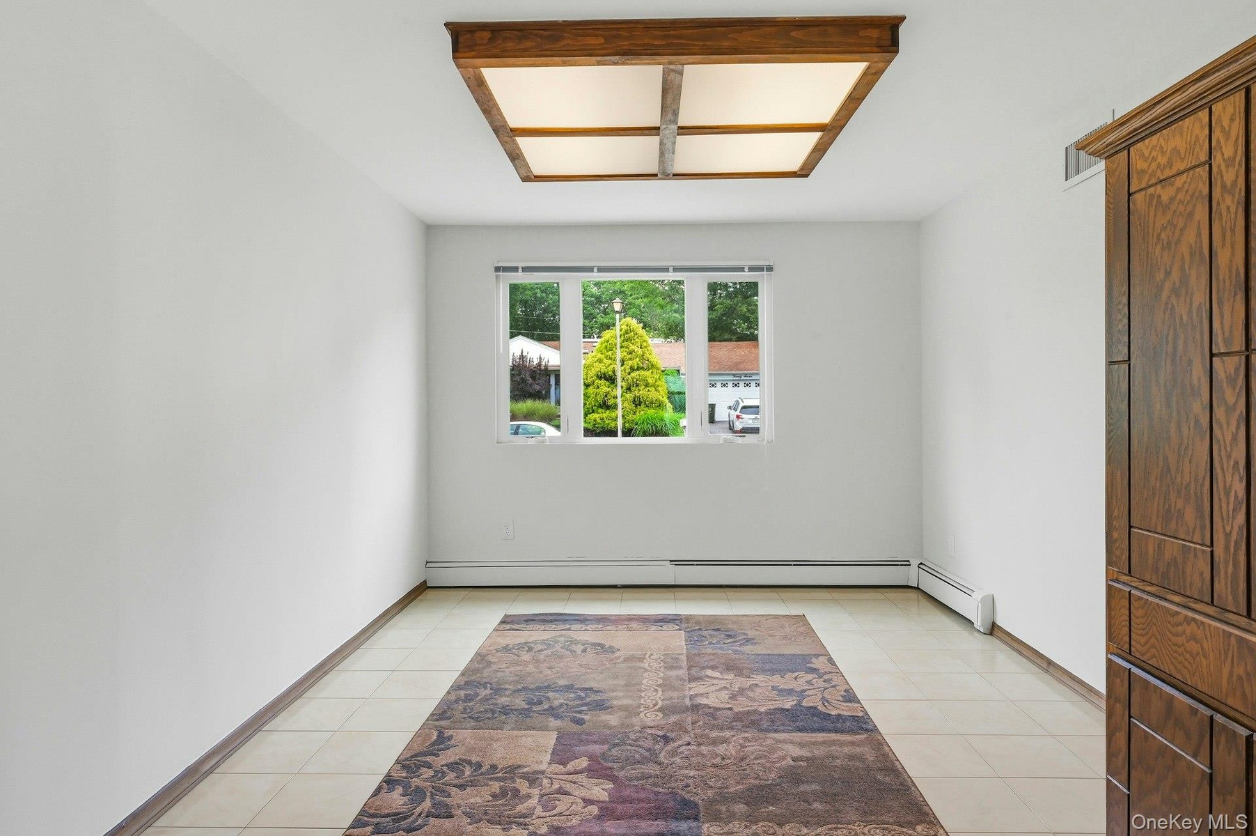 Bright room with a three-panel window, white walls, and light-toned tile flooring