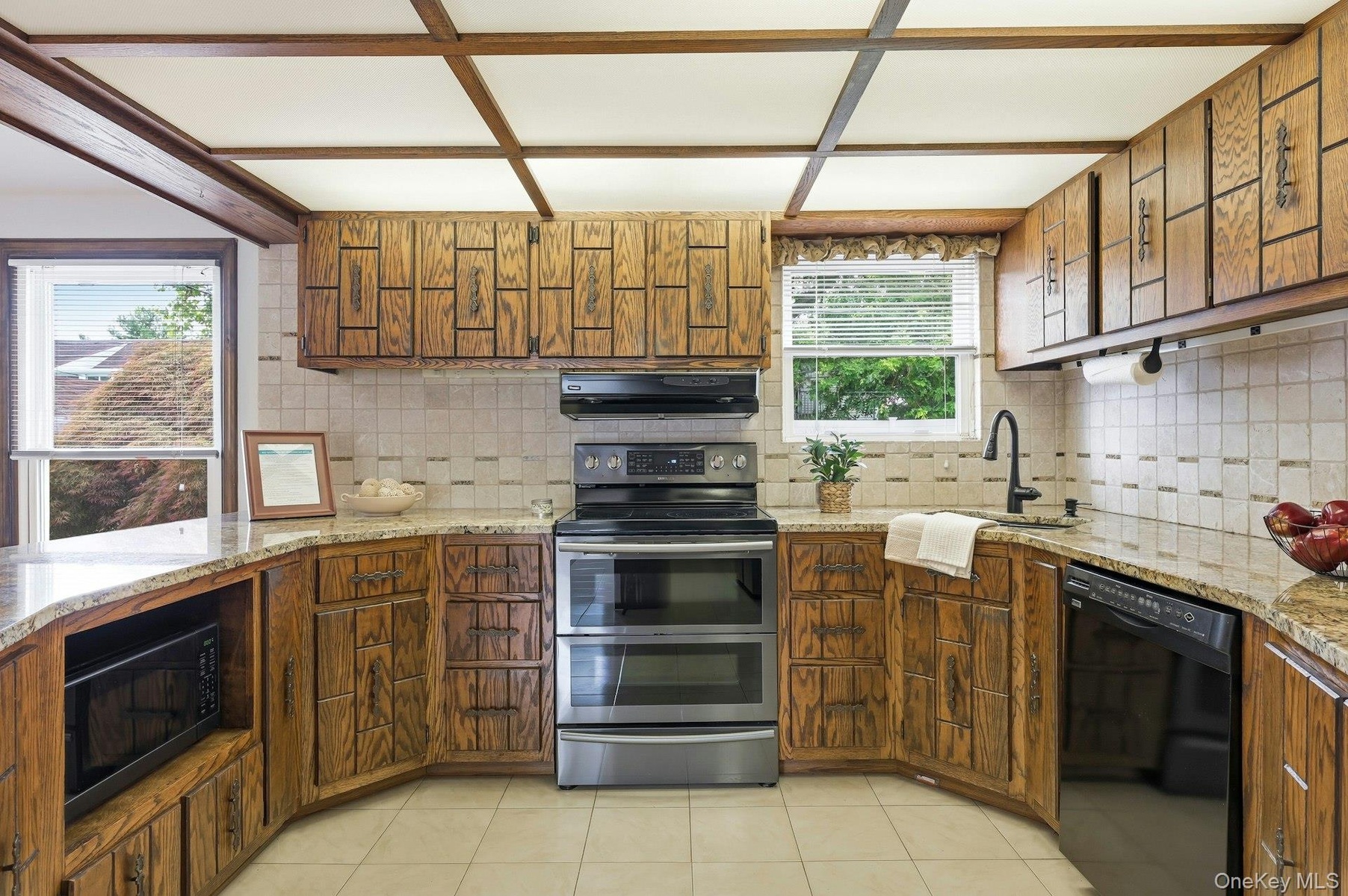Kitchen featuring wood cabinetry, light-toned tiled backsplash, granite-finish countertops, and a full suite of appliances including a double oven ran