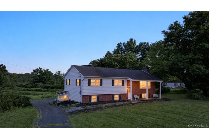 Single-story home featuring a combination of white siding and brick facade, a covered front porch, and a dark shingle roof