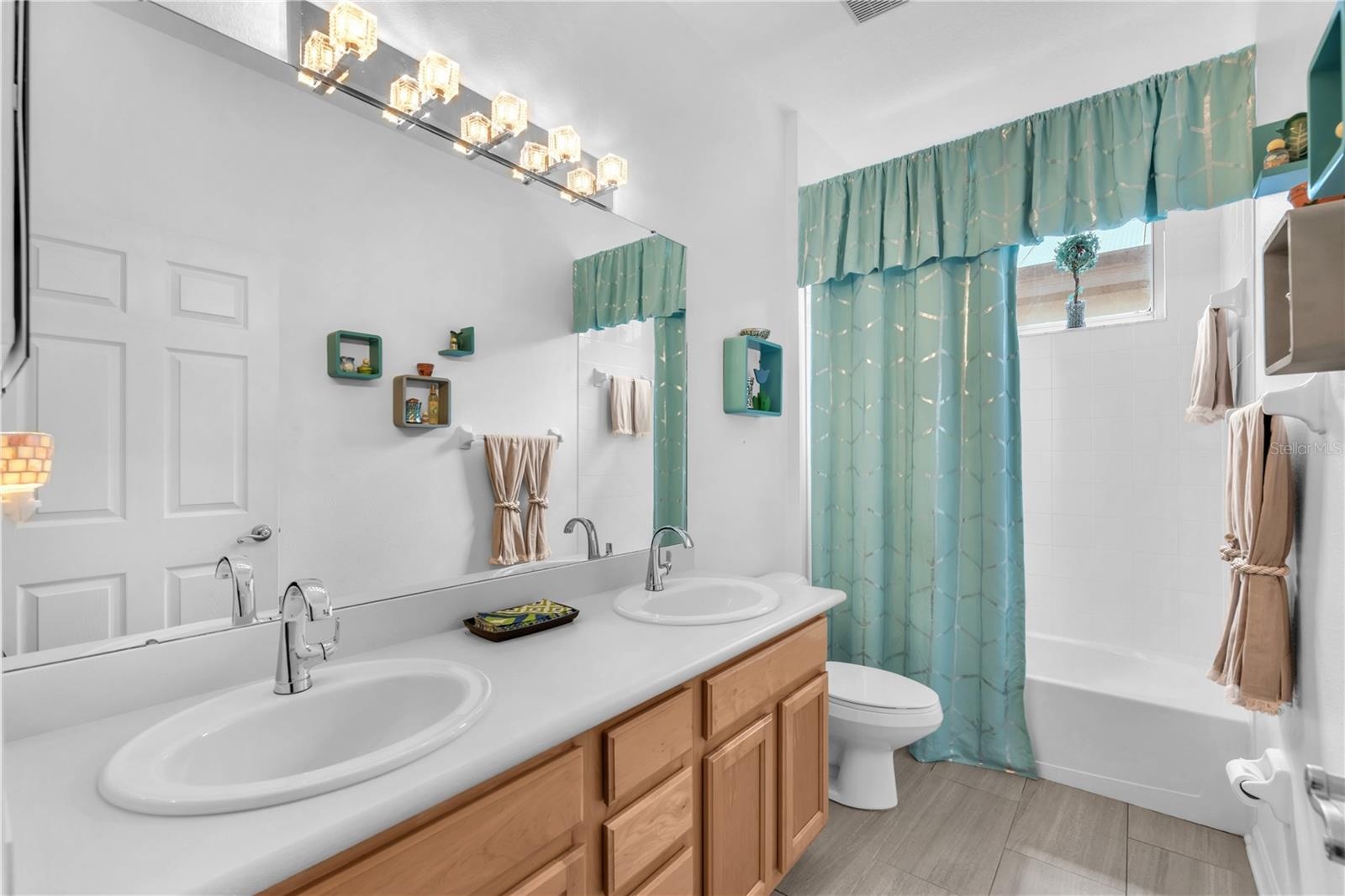 well-appointed guest bath with dual vanities and a tub/shower combination.