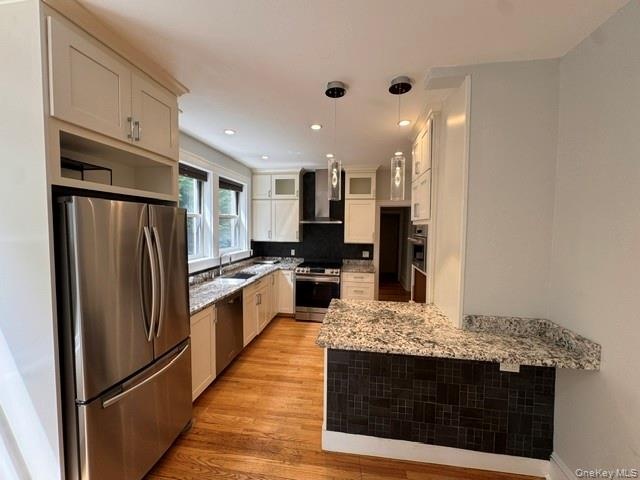 Well-appointed kitchen featuring light-toned cabinetry, stainless steel appliances, granite countertops, and hardwood flooring