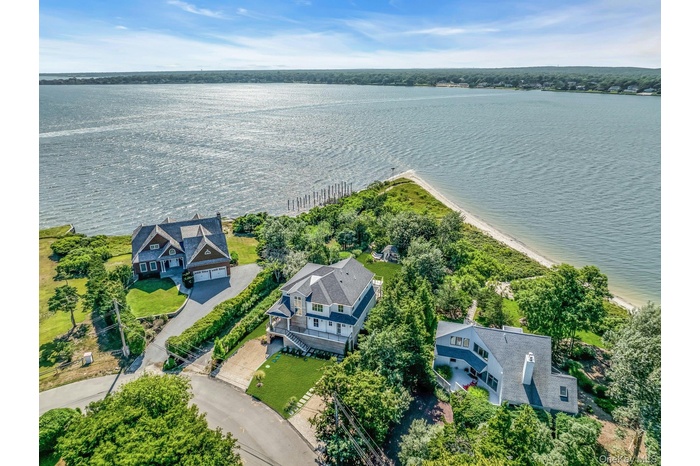 Waterfront property featuring extensive shoreline access, a private beach, and lush green landscaping