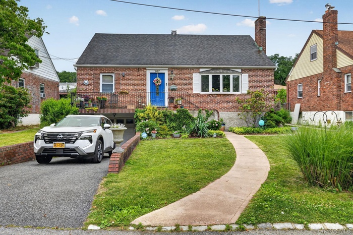 Brick exterior residence featuring a prominent bay window with white shutters, a distinctive blue entry door, and a dedicated driveway