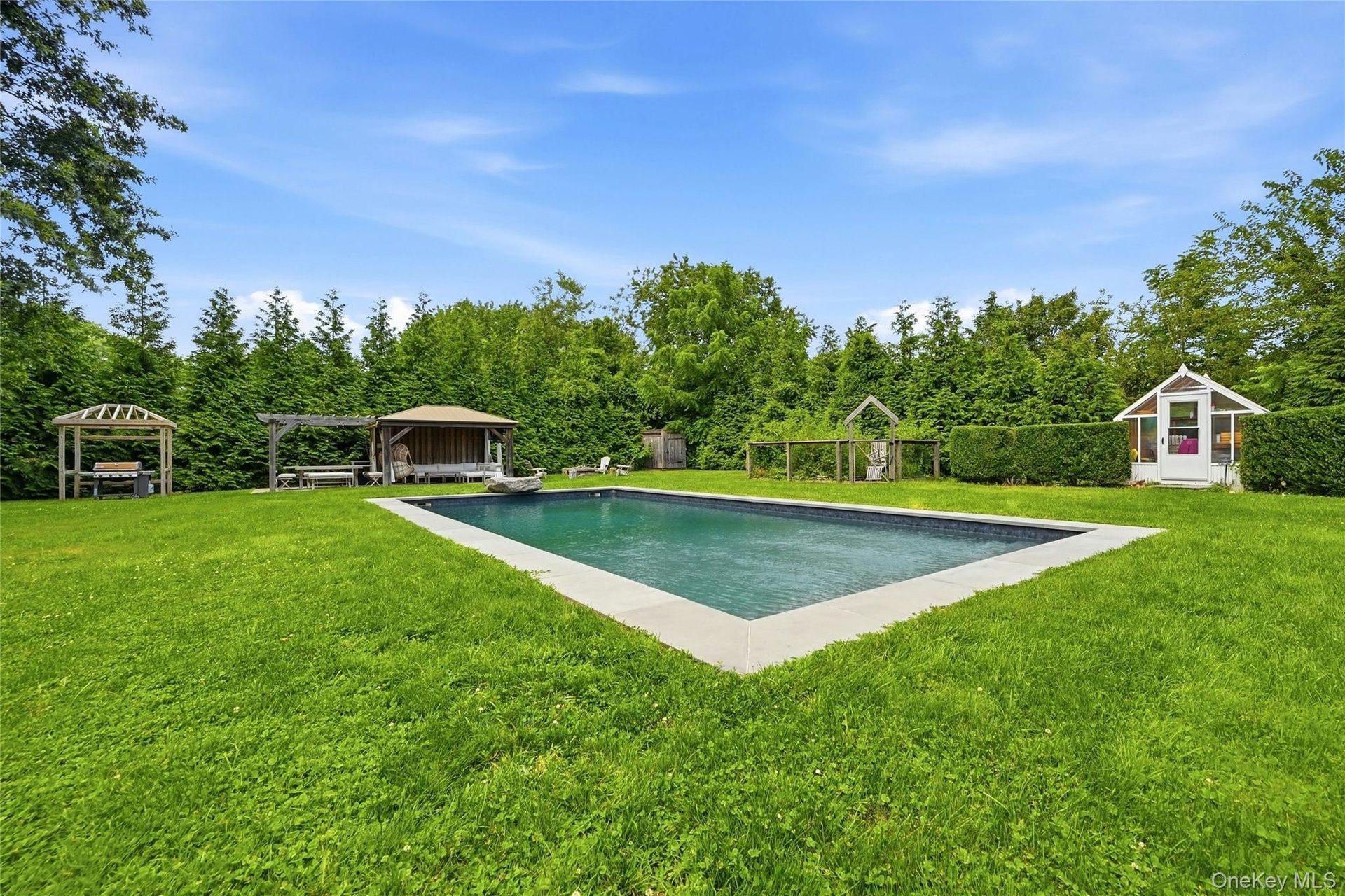 Rectangular inground salt water pool with stone coping, entertaining cabana in the back-ground