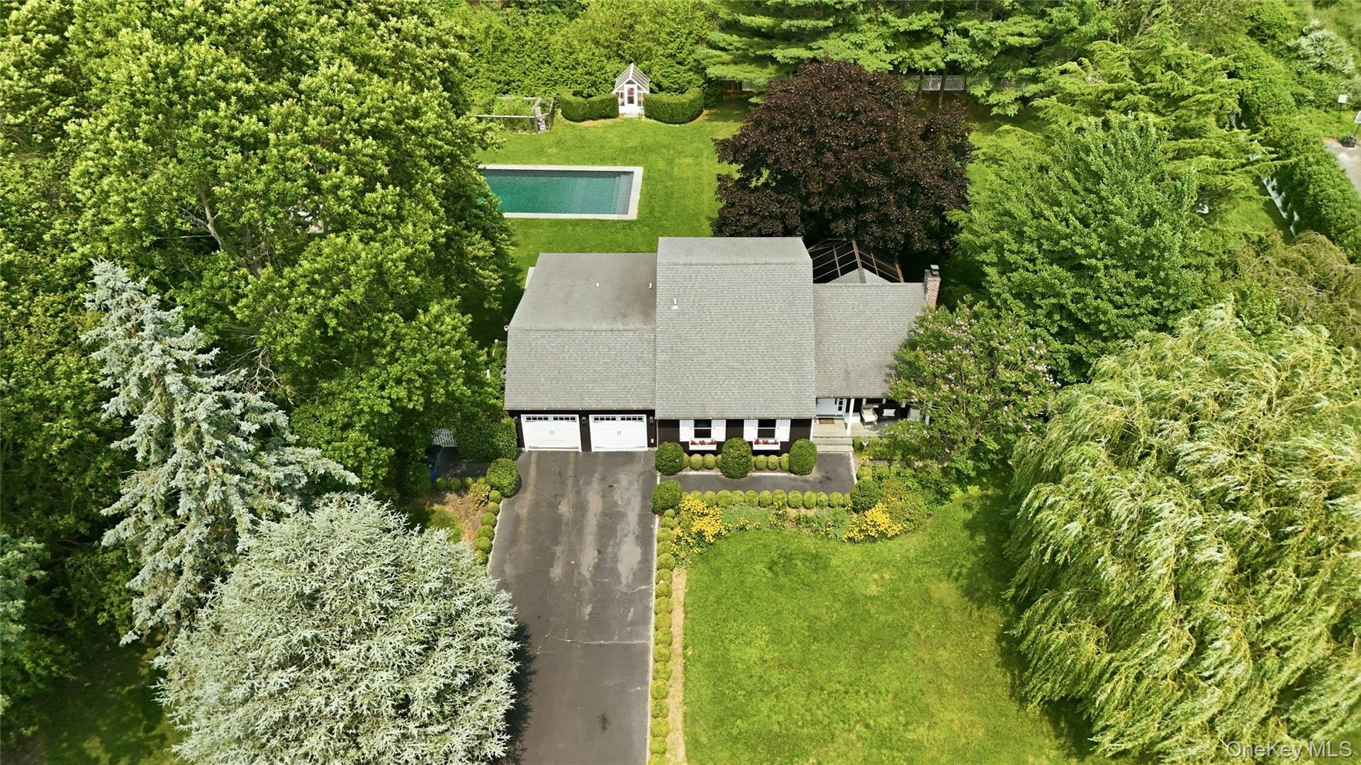 Ranch-style residence featuring a prominent two-car garage, asphalt driveway, and a shingle roof