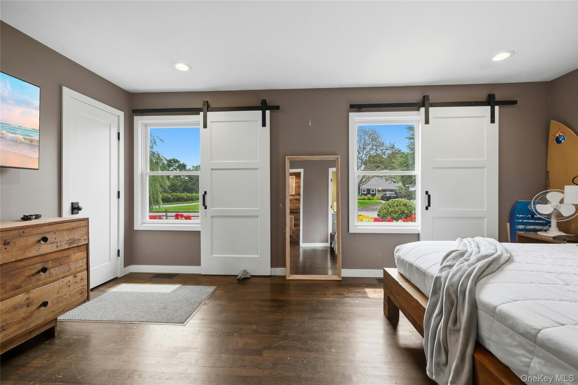 Hardwood-style flooring throughout this space features two windows with barn door style coverings, recessed ceiling lighting, and a solid white interi