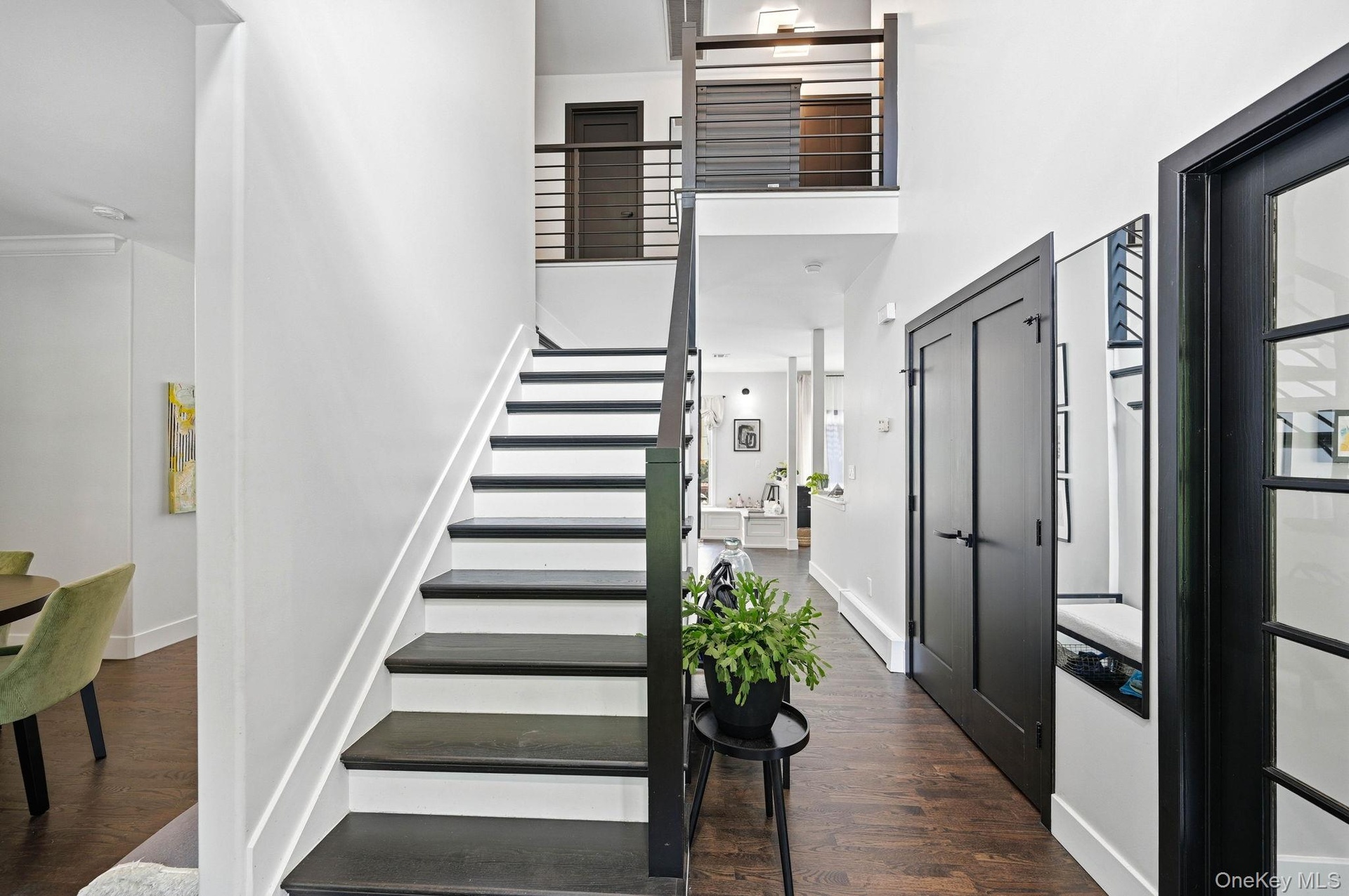 Entryway featuring dark wood-finish flooring and a black staircase with horizontal metal balusters