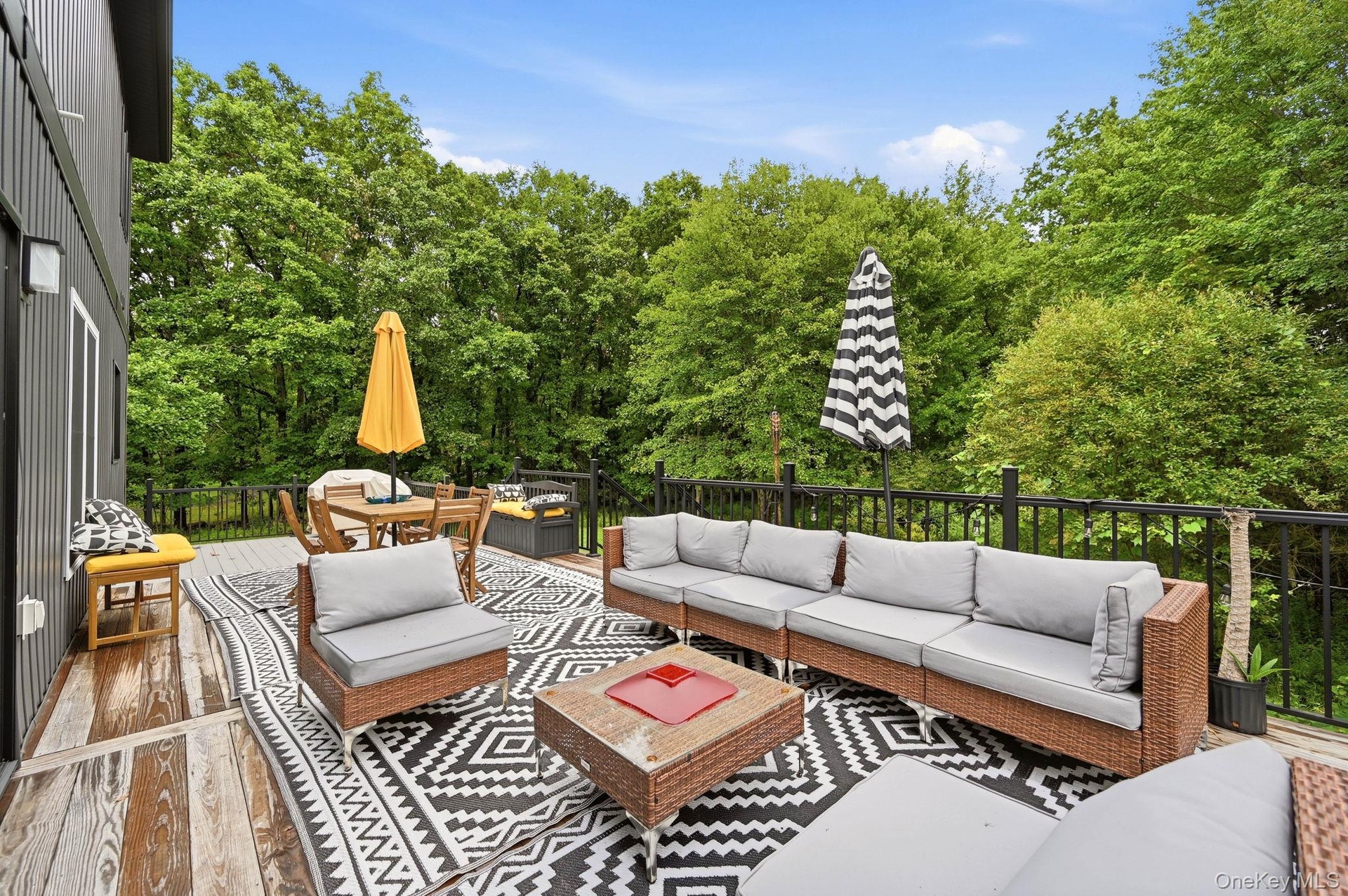 An expansive outdoor deck designed for relaxing and entertaining, featuring multiple seating areas and plenty of room for dining and gatherings. Surro