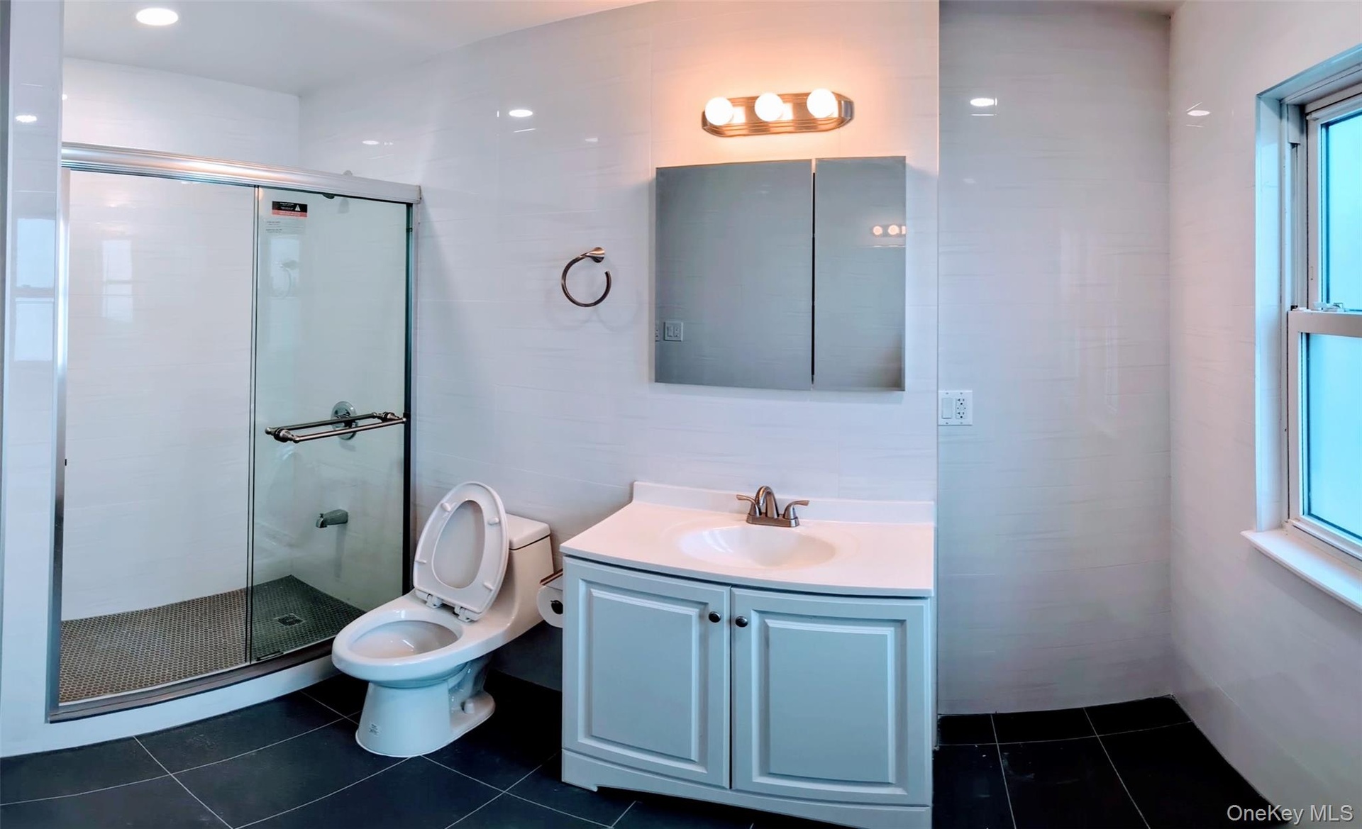 Bathroom with toilet, tile patterned floors, vanity, and a stall shower