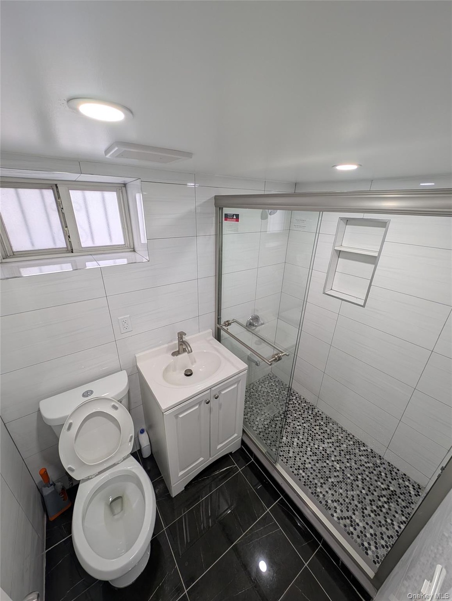 Bathroom featuring a shower stall, vanity, visible vents, toilet, and marble finish floor