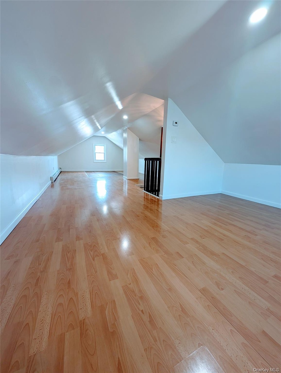 Additional living space with baseboards, vaulted ceiling, and wood finished floors