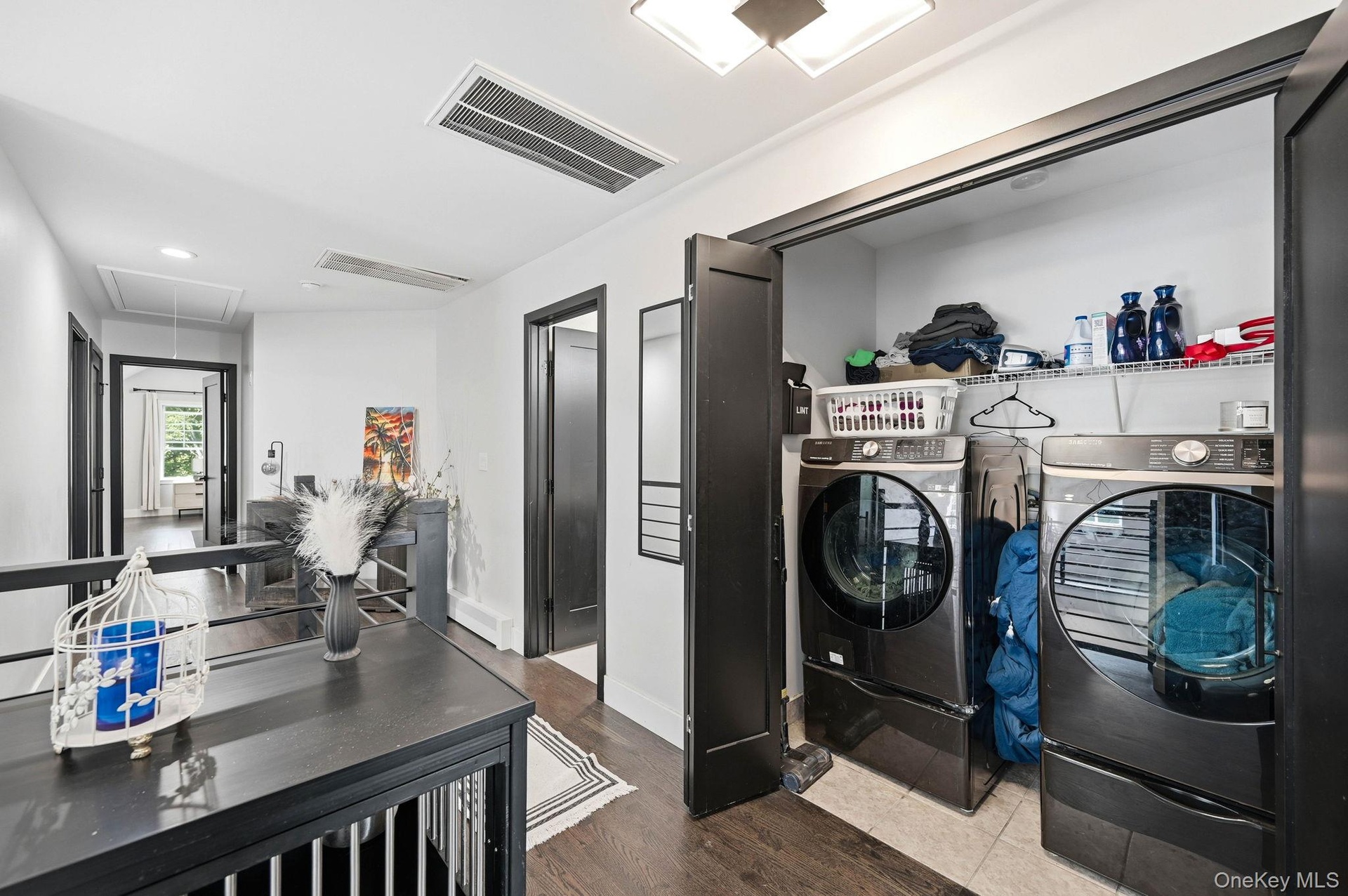 Convenient second-floor laundry closet featuring a full-size washer and dryer, built-in shelving and double doors for easy access. Thoughtfully positi