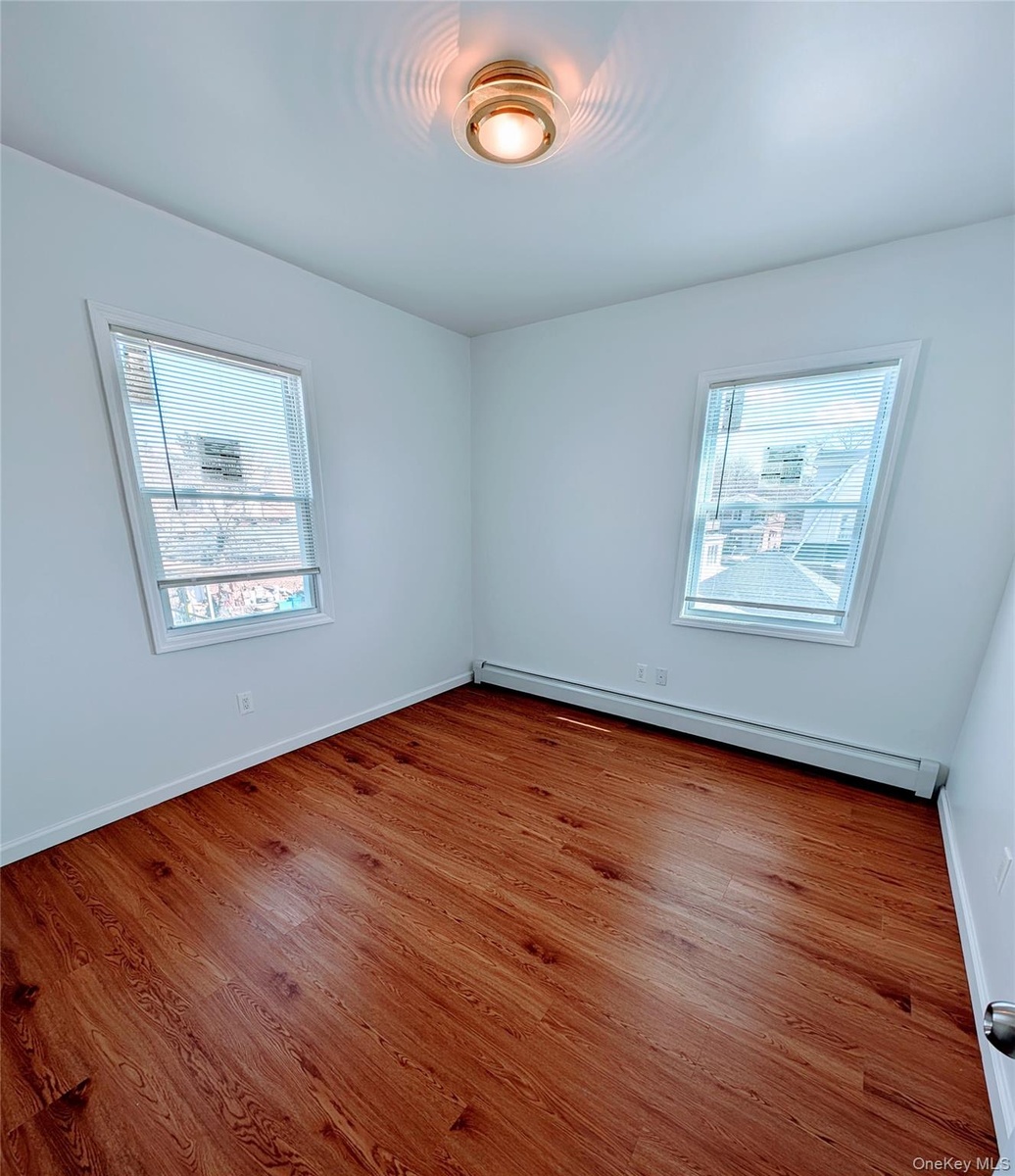 Spare room with baseboard heating, baseboards, and wood finished floors