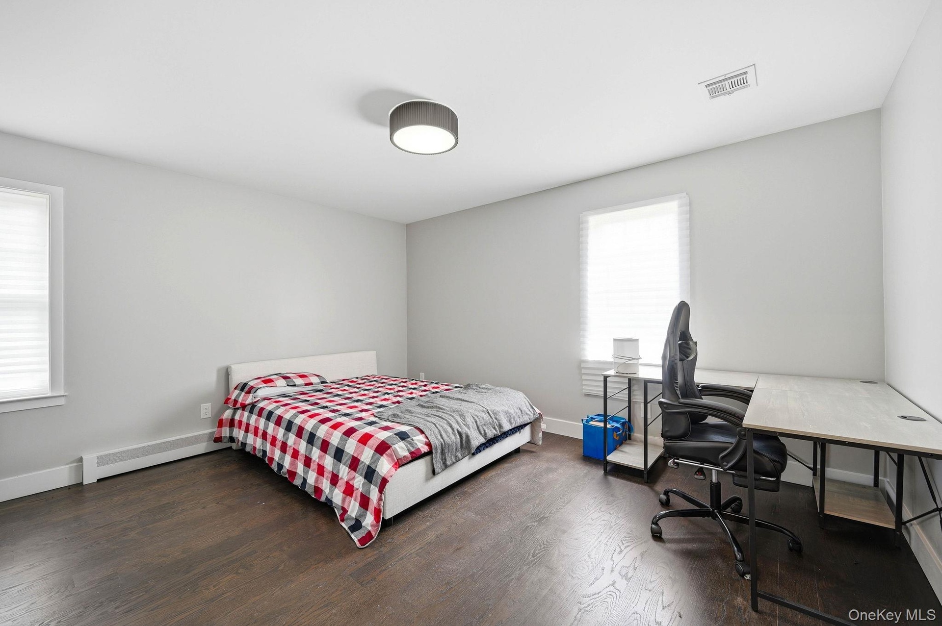 Spacious room featuring wood-finish flooring, light grey painted walls, and white baseboards