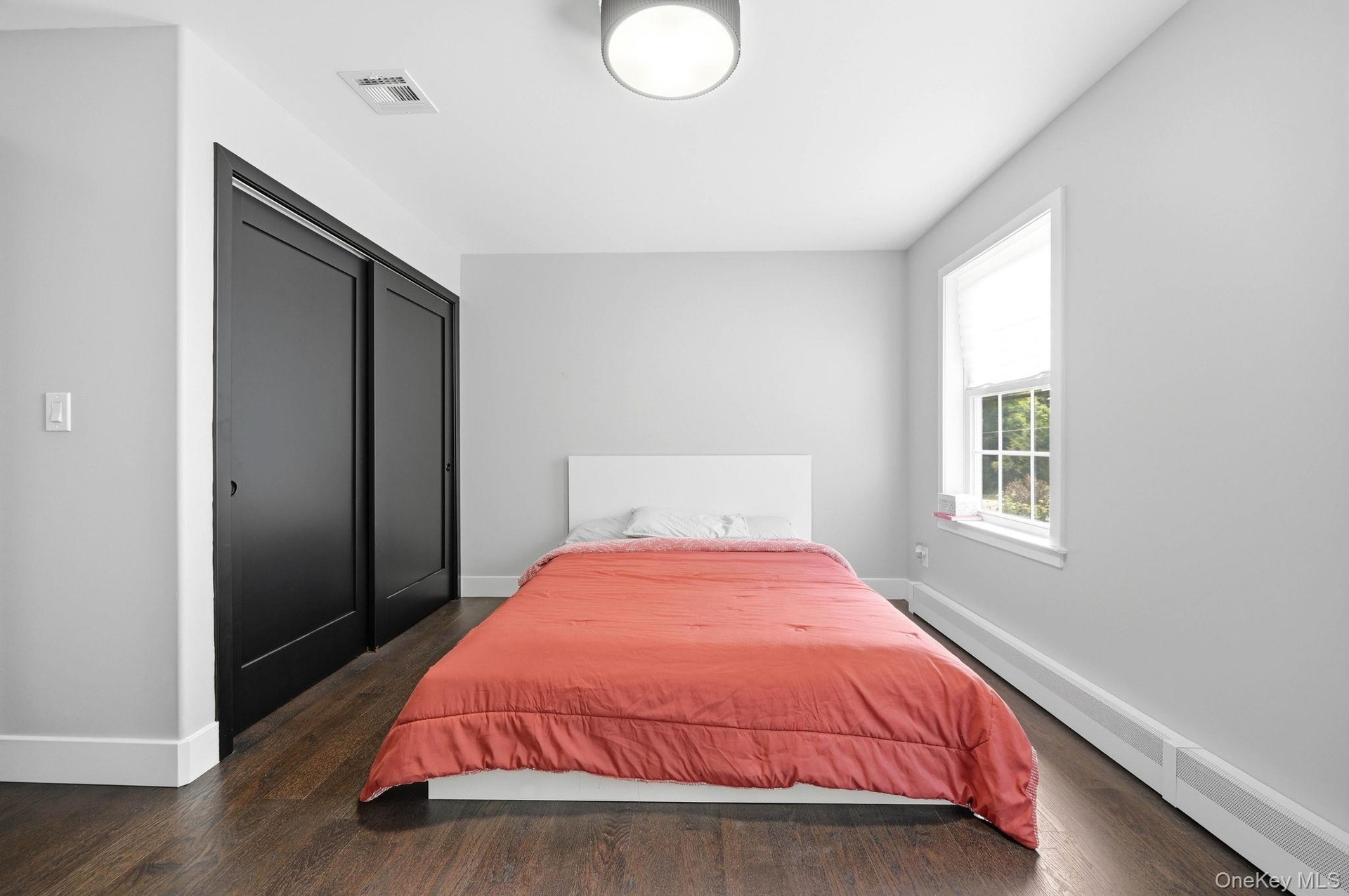 Bedroom featuring dark wood-finish flooring, light gray walls, and white trim
