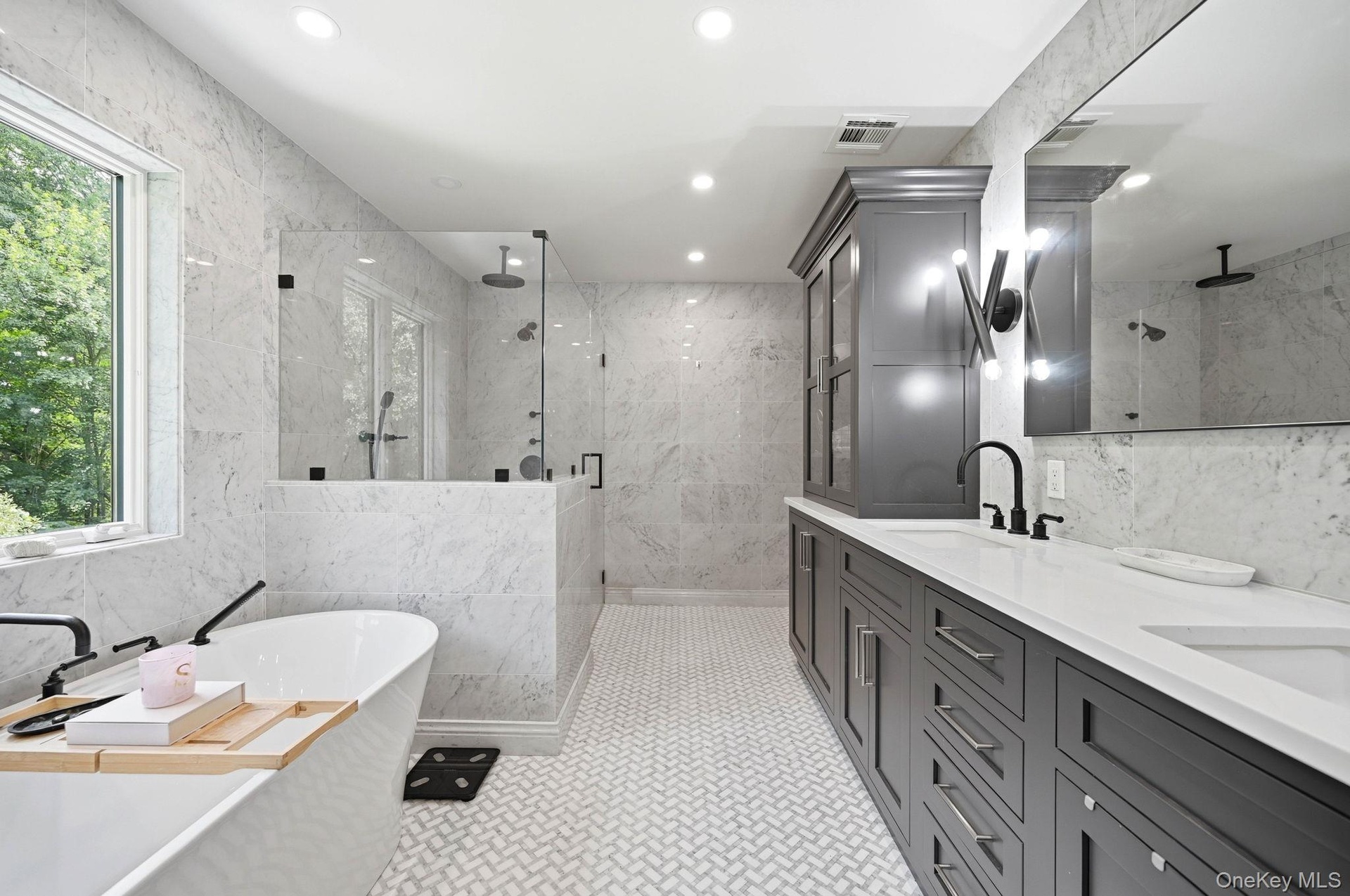 Spacious bathroom featuring a Fleurco Opus Collection freestanding soaking tub, a large glass-enclosed shower, dual vanity with undermount sinks, cust