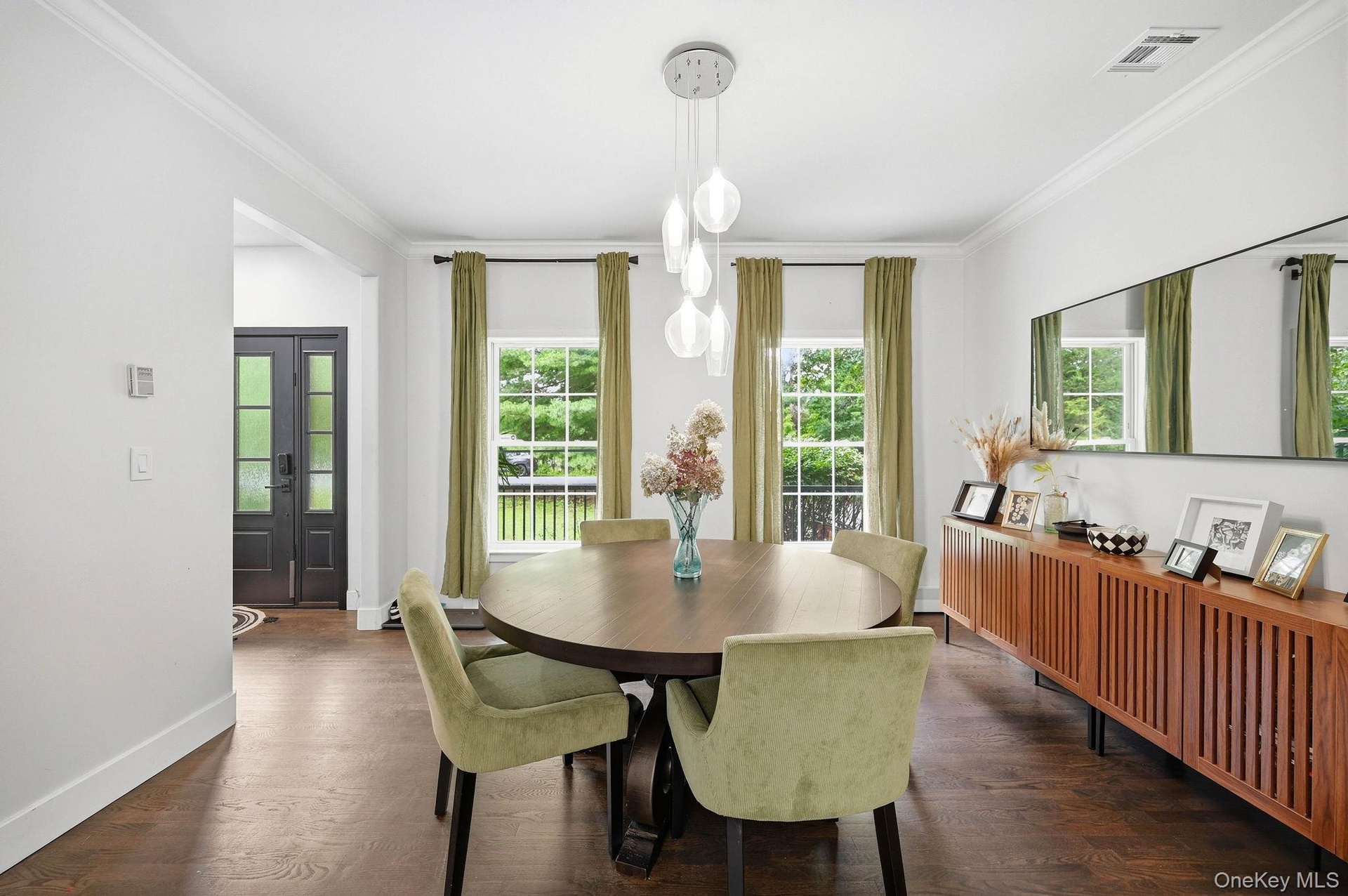 Dining area featuring wood-finish flooring, a contemporary chandelier, crown molding, and multiple windows providing lots of natural light