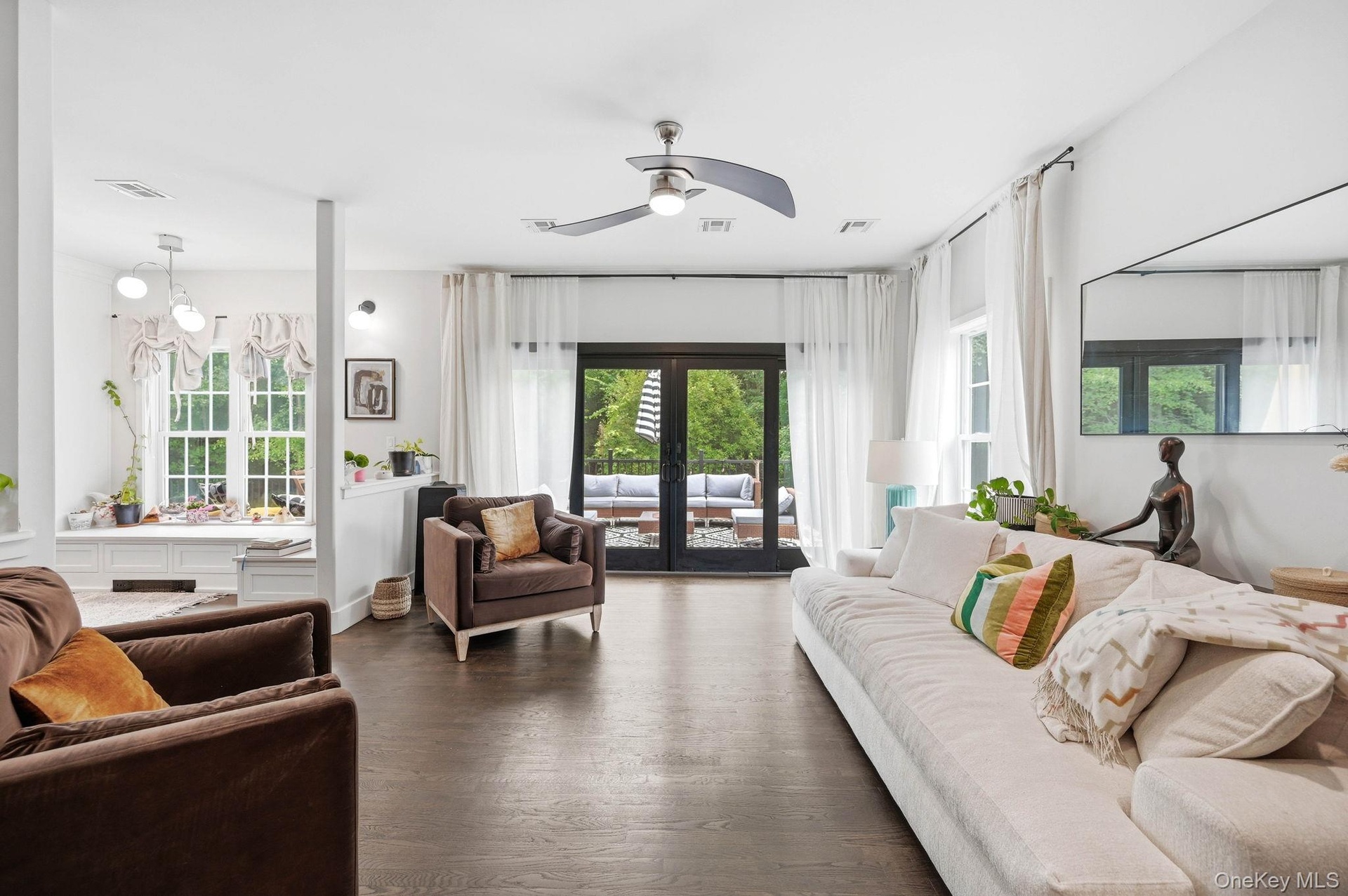 Living area featuring dark wood-finish flooring, a modern ceiling fan, and white walls