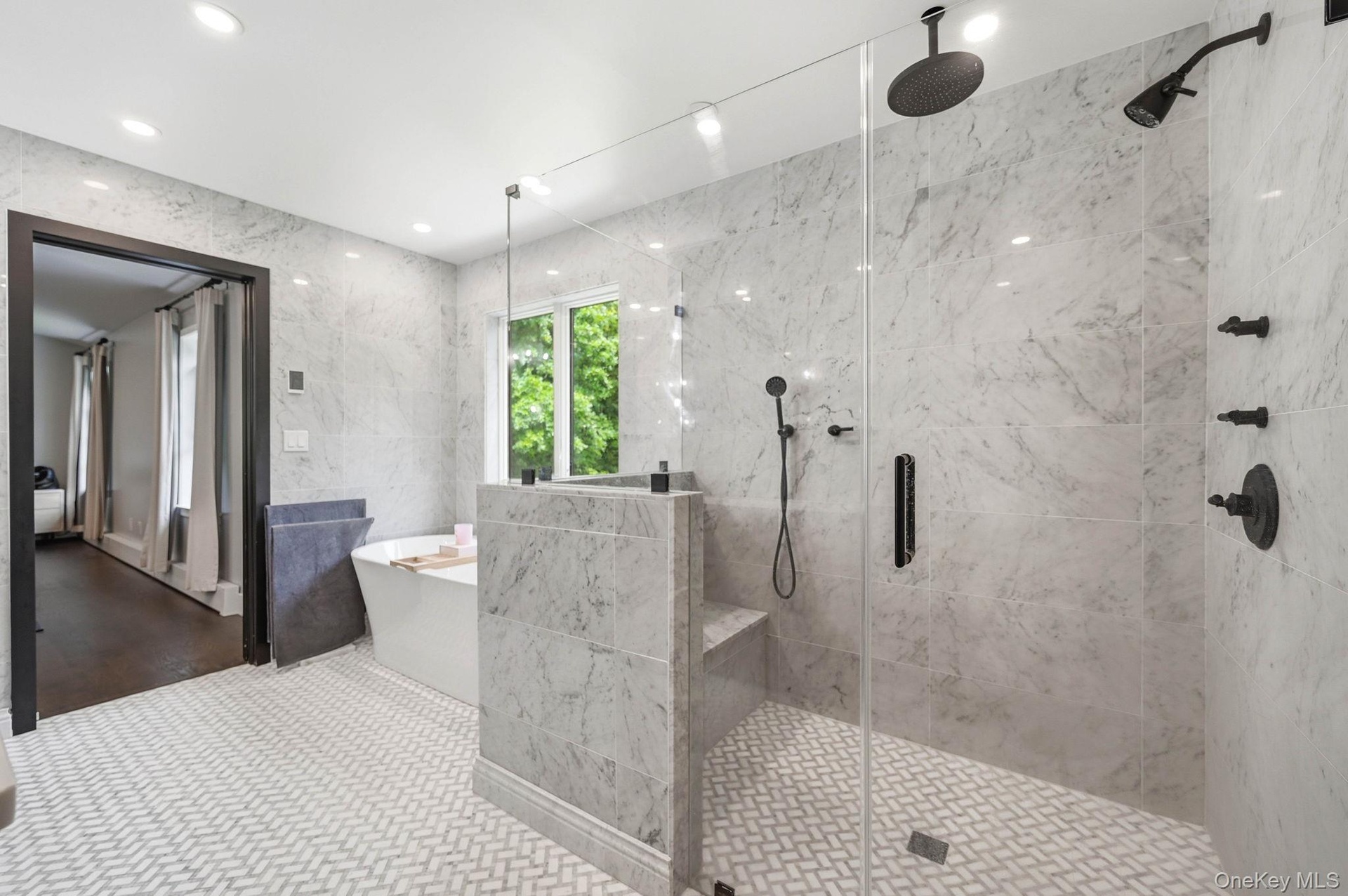 Spacious bathroom featuring a frameless glass shower enclosure, matte black fixtures, and a built-in shower bench