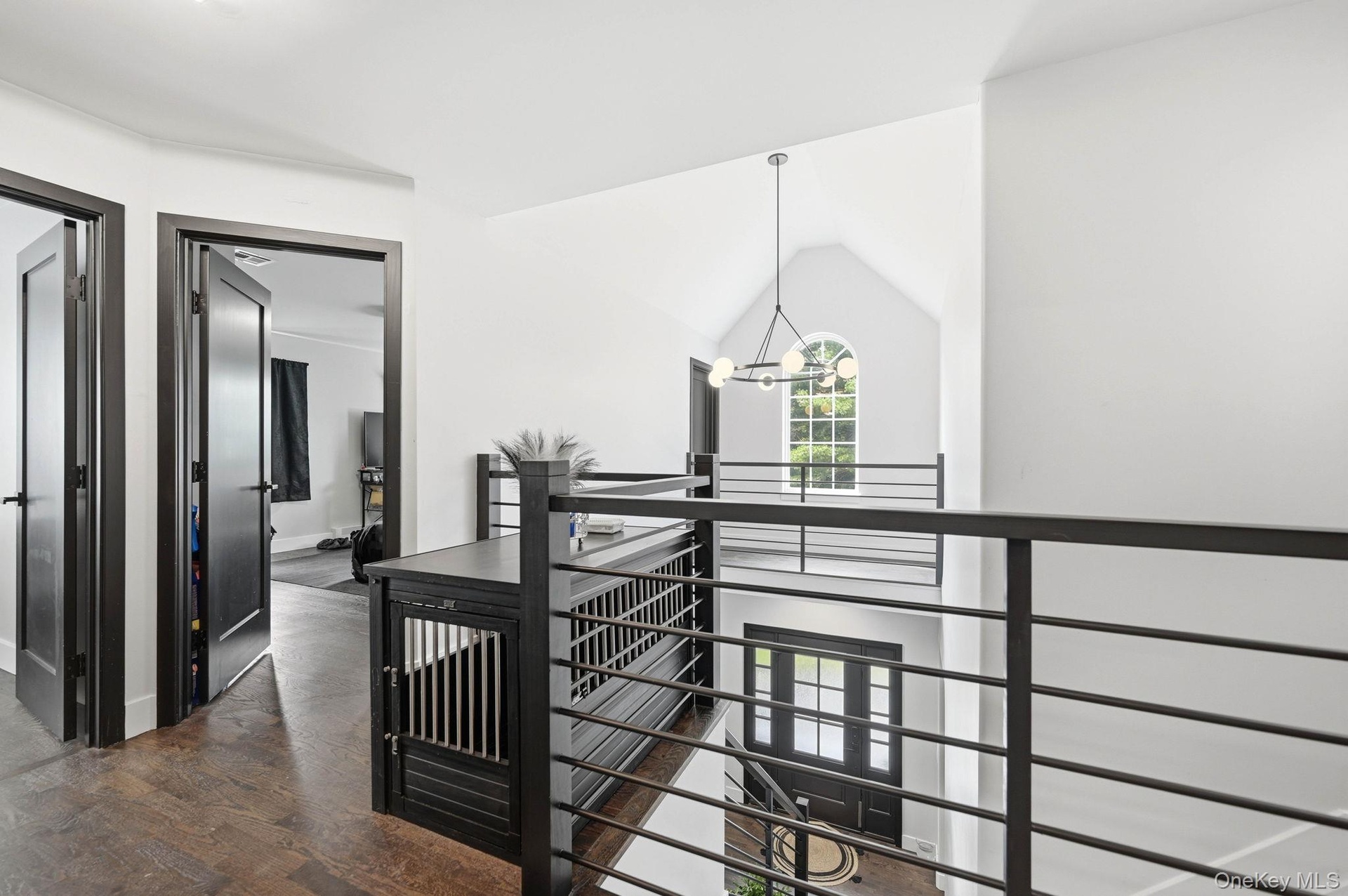 A dramatic second-floor overlook showcases the home’s cathedral-ceiling foyer and striking arched window, filling the space with natural light. Modern