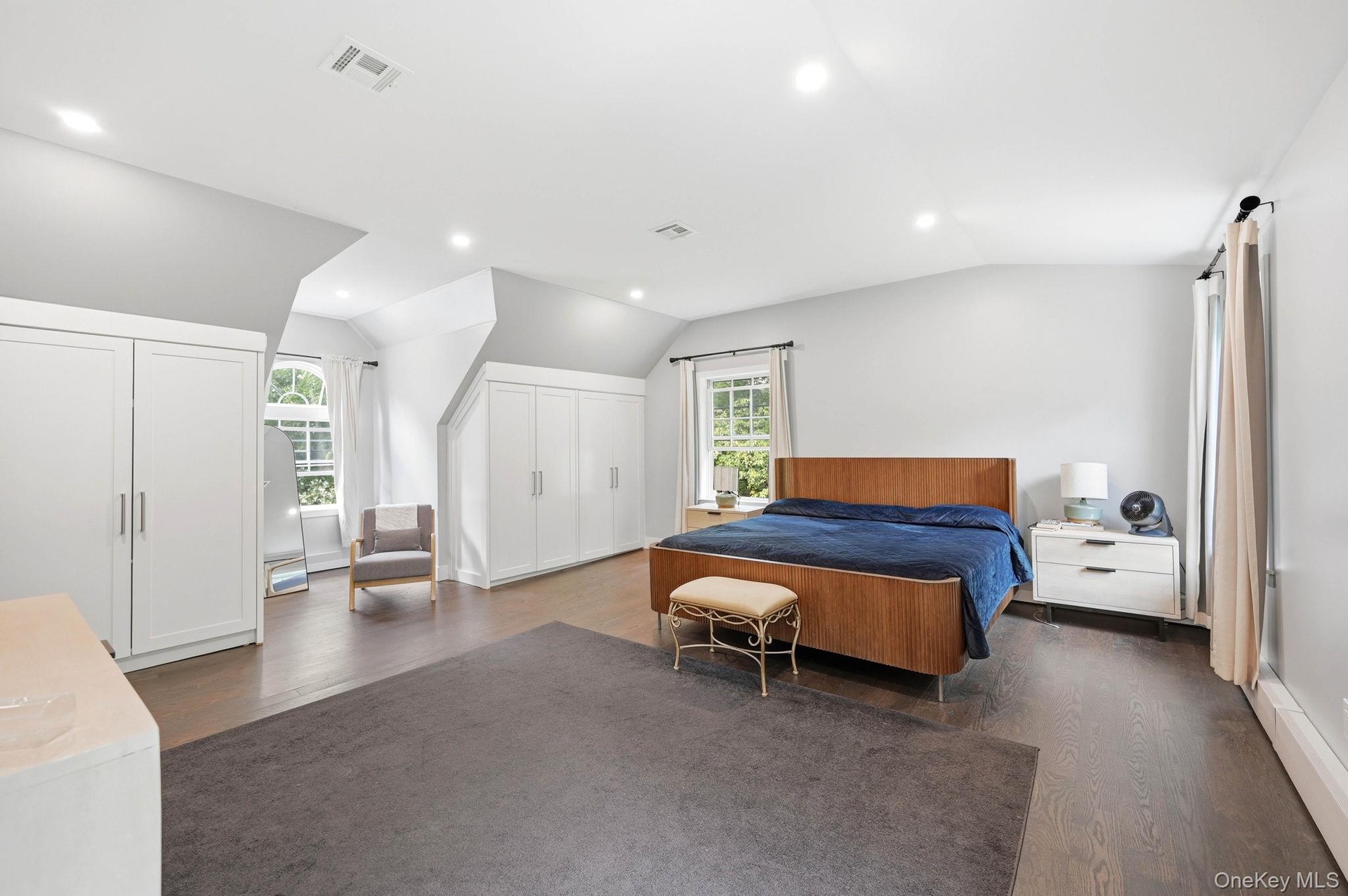 Spacious room featuring wood-finish flooring, recessed lighting, and multiple built-in storage units