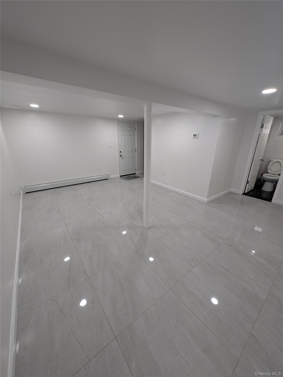 Basement with a baseboard radiator, recessed lighting, marble finish floor, and baseboards