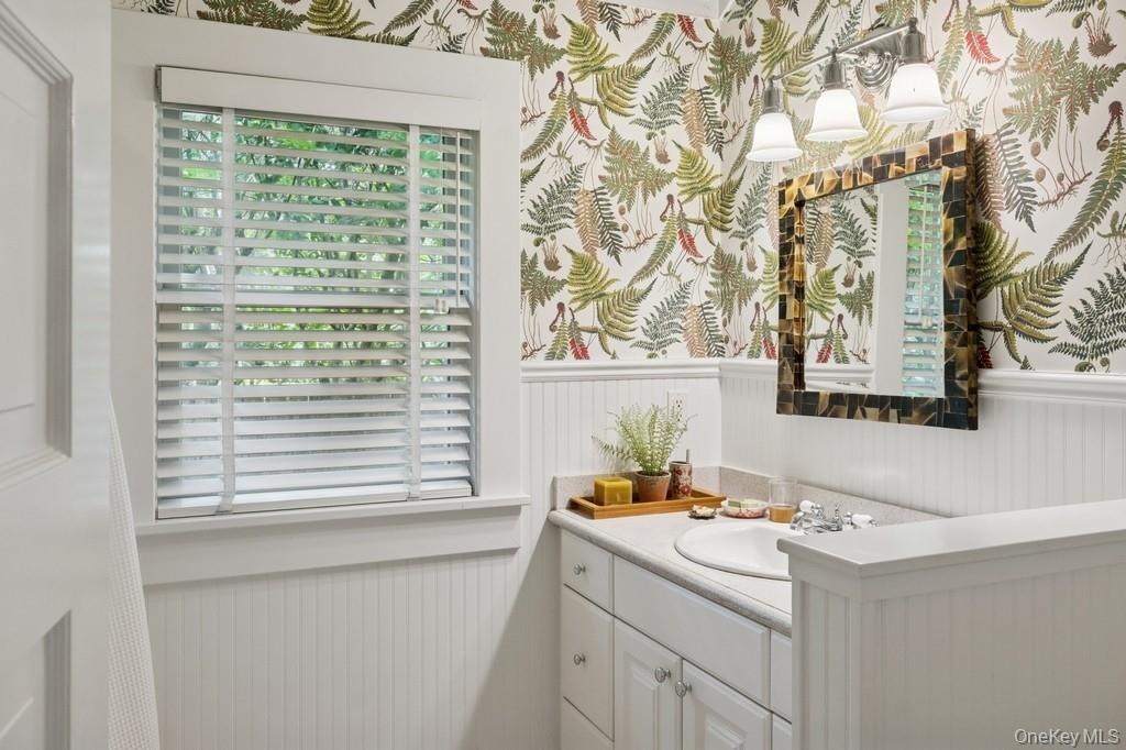 Bathroom with wainscoting, vanity, and wallpapered walls