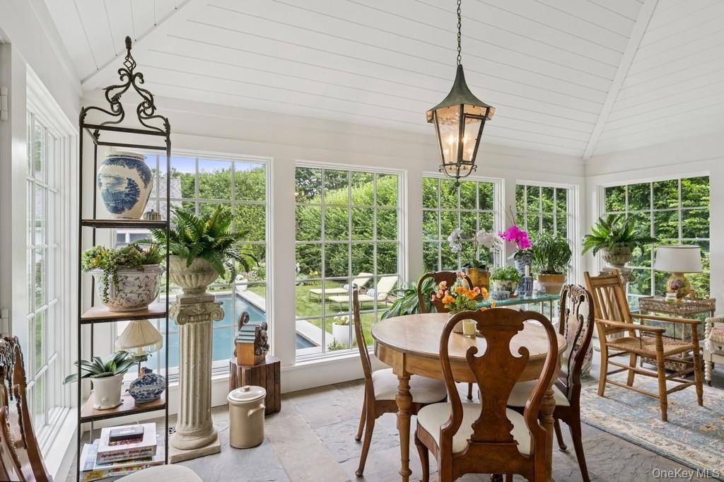 Sunroom with lofted ceiling, plenty of natural light, stone tile flooring, and wooden ceiling