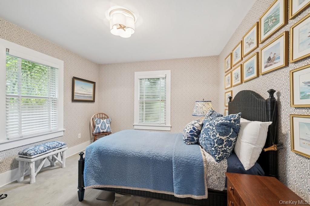 Bedroom with multiple windows, wallpapered walls, and wood finished floors