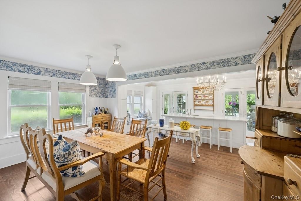 Dining room with wood finished floors, wallpapered walls, crown molding, and a chandelier