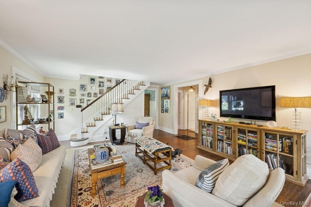 Living area featuring stairway, crown molding, and wood finished floors