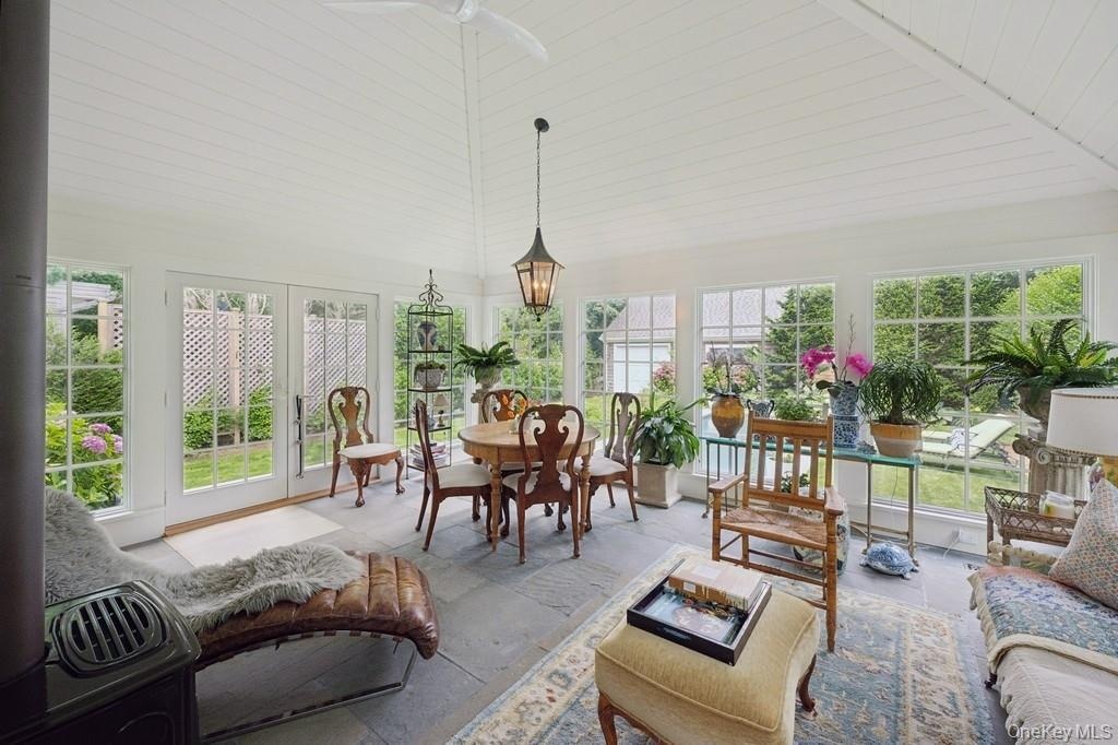 Sunroom / solarium featuring french doors, high vaulted ceiling, and stone finish floors