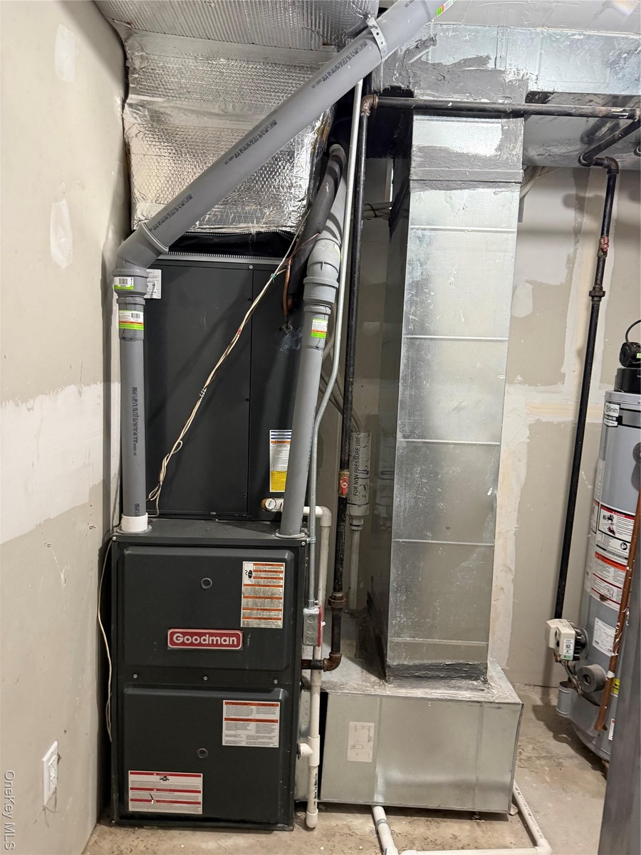 Utility room featuring heating unit and water heater