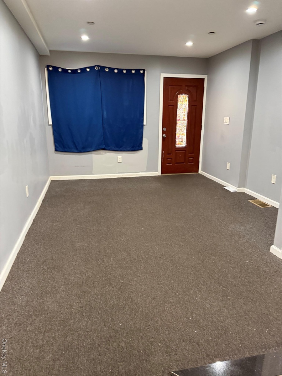Foyer with dark colored carpet and recessed lighting