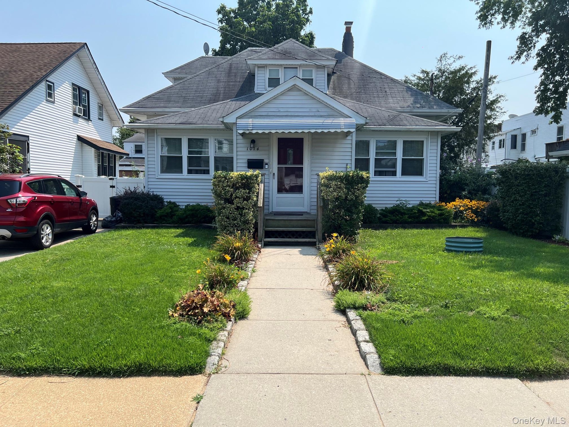 Front exterior featuring white siding, a prominent dormer, and a covered entry