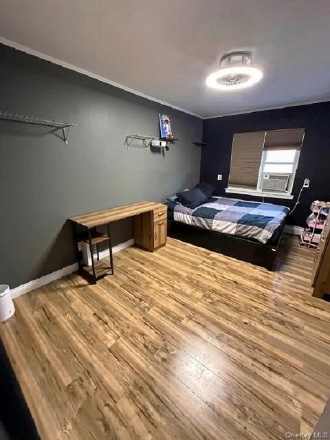Wood-finish flooring throughout, ceiling-mounted light fixture, light-colored trim, and a window with blinds