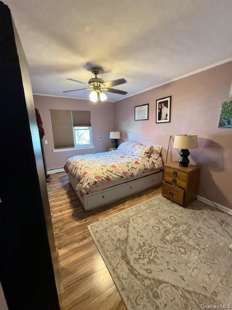 Wood-finish flooring with crown molding and ceiling fan with integrated lighting