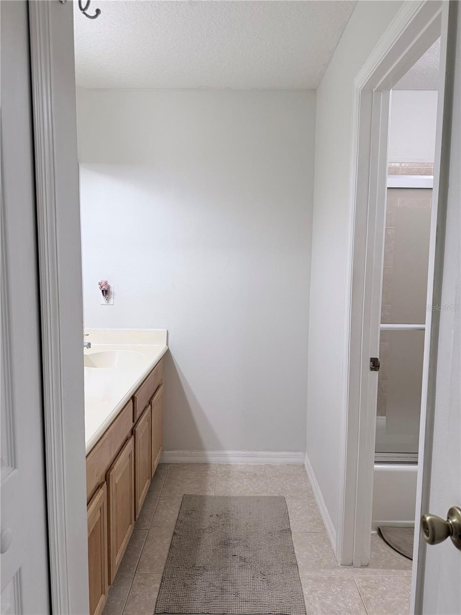 The spacious secondary bathroom features a double-sink vanity and a convenient linen closet for added storage.