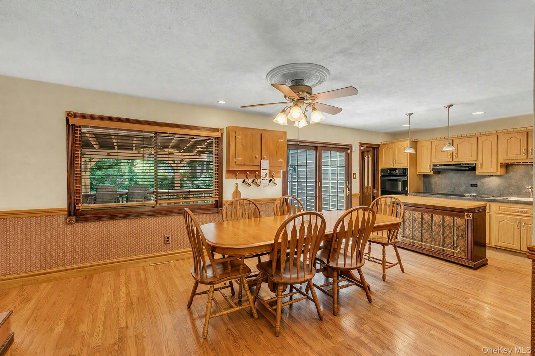 Spacious open-concept dining and kitchen area featuring warm wood-finish flooring throughout, a round pedestal dining table with seating for four, cus