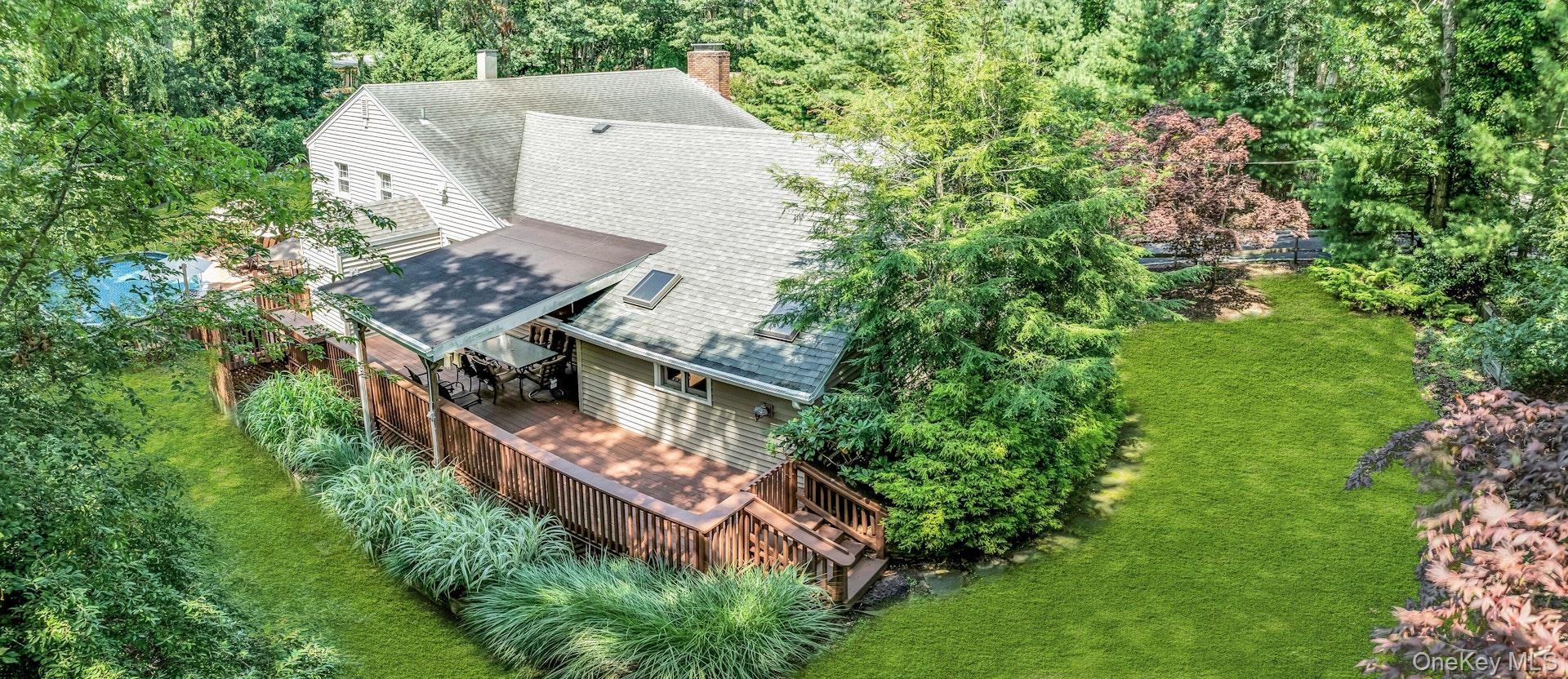 Expansive backyard oasis featuring a composite deck with integrated seating areas, mature landscaping with specimen trees and shrubs, and manicured la
