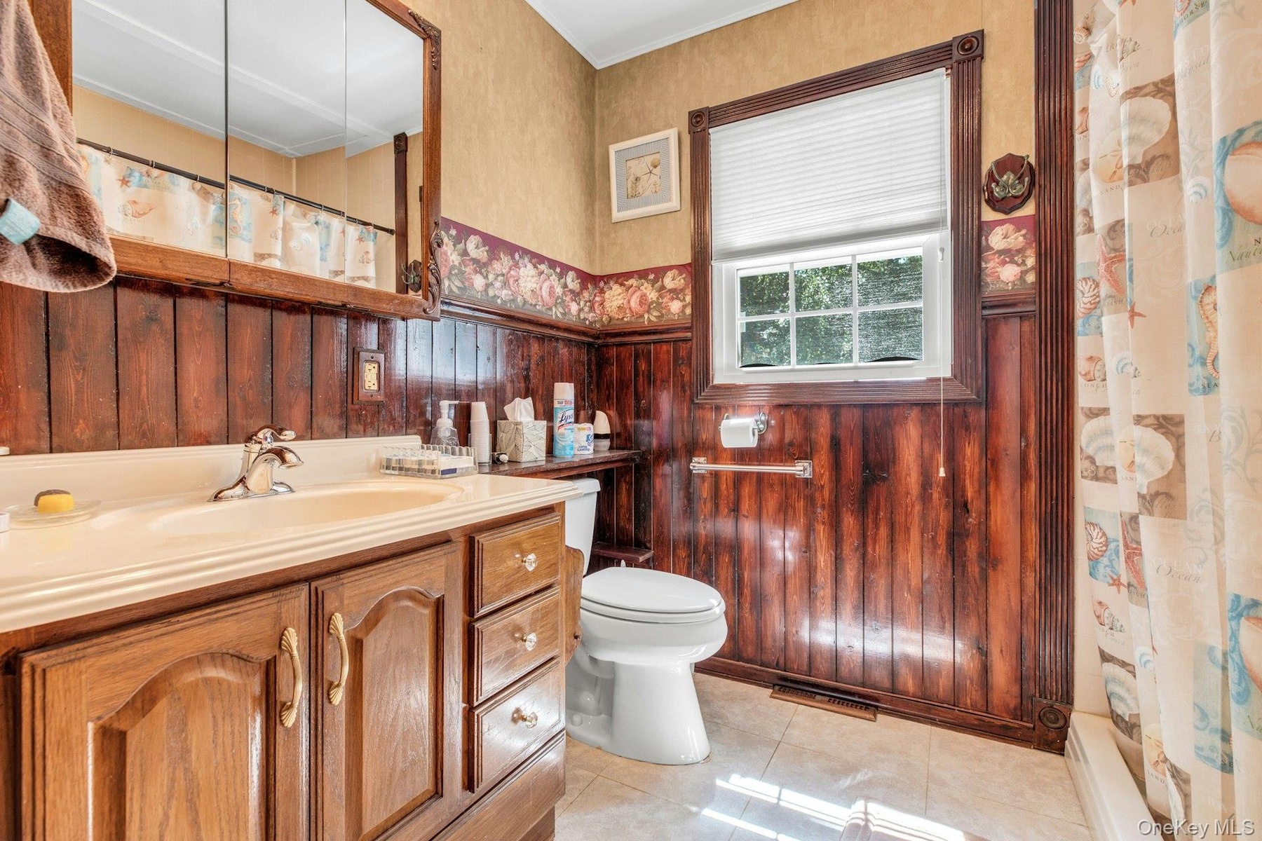 Classic bathroom featuring rich wood cabinetry with multiple drawers and storage, ceramic sink with chrome fixtures, and white ceramic toilet
