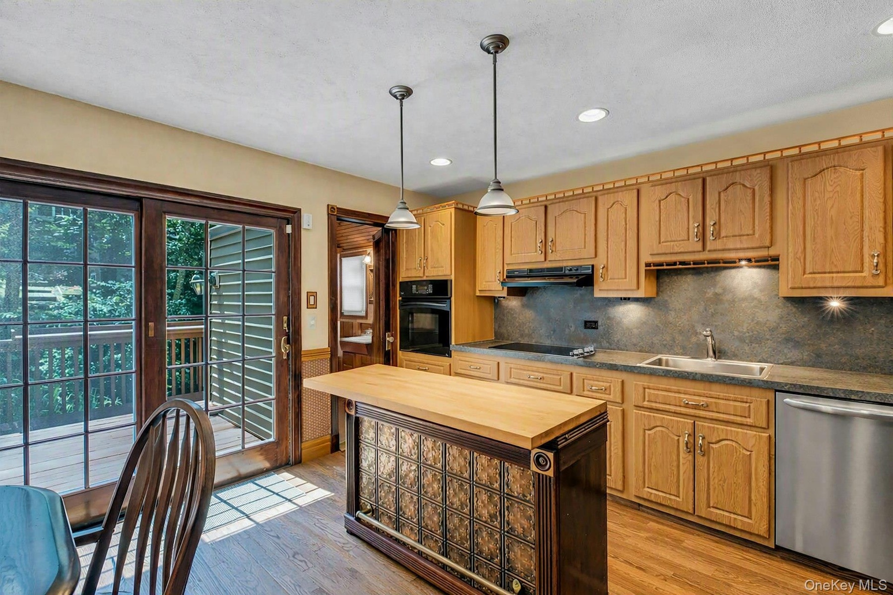 Kitchen features wood cabinetry, dark countertops, and a stainless steel dishwasher