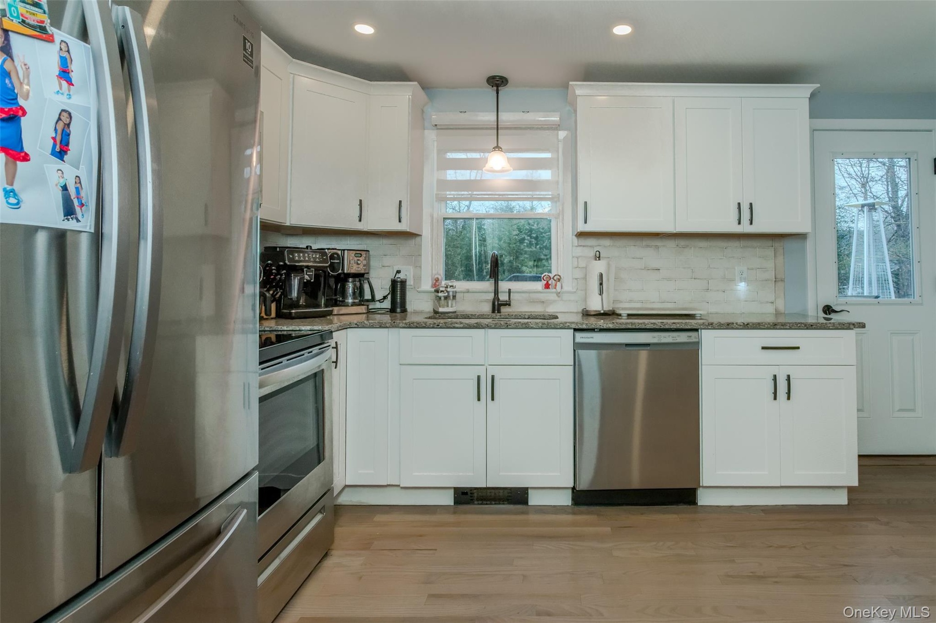 Kitchen with light hardwood / wood-style flooring, white cabinets, a healthy amount of sunlight, and appliances with stainless steel finishes