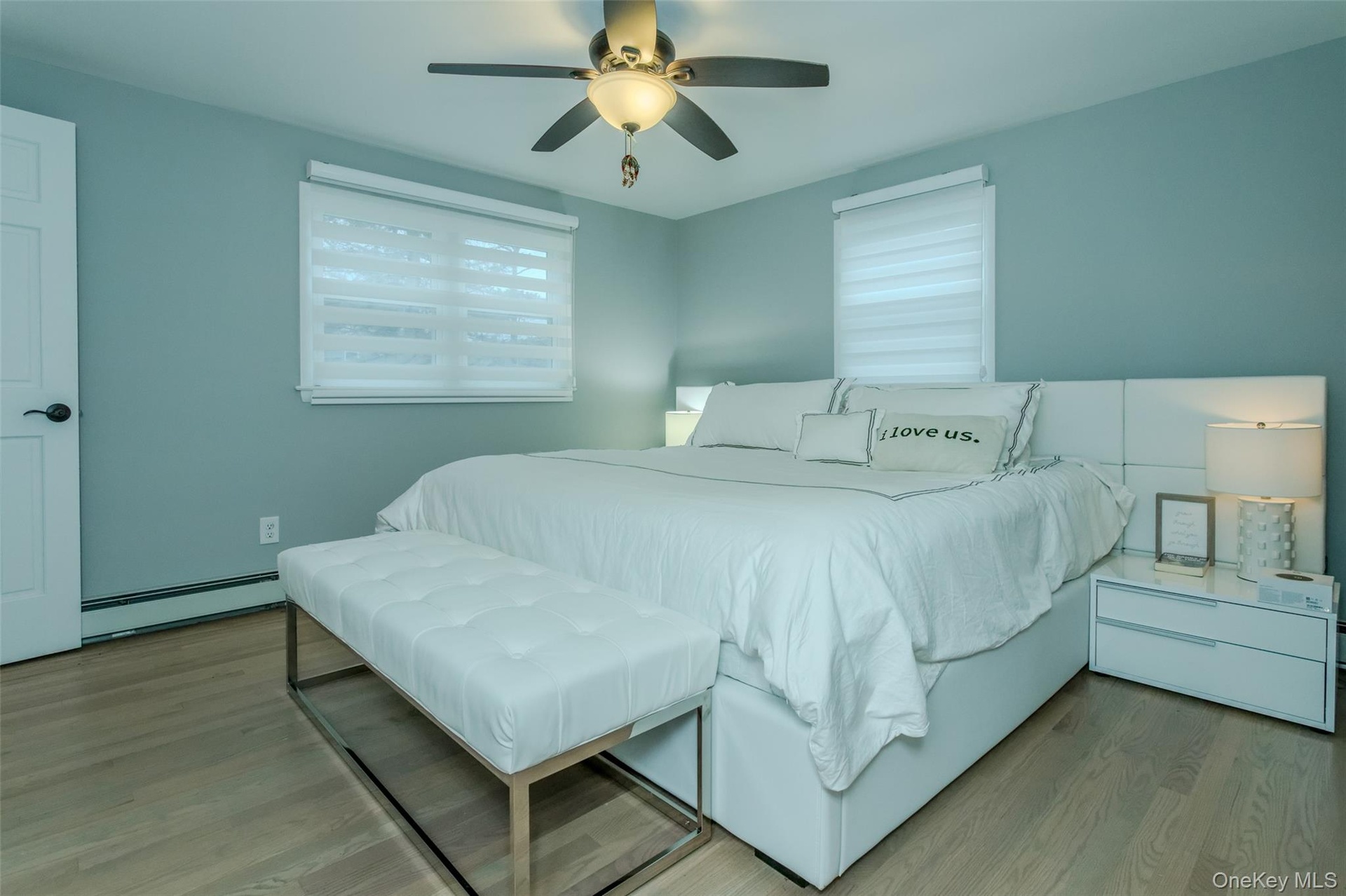 Bedroom with ceiling fan, light wood-type flooring, and a baseboard radiator