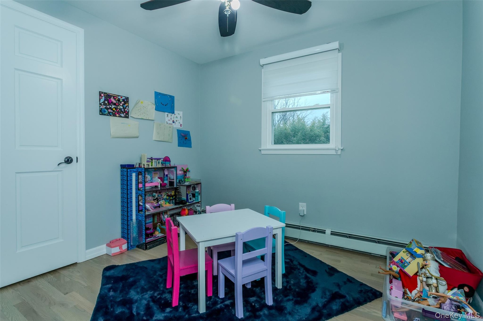 Recreation room with wood-type flooring, ceiling fan, and a baseboard heating unit