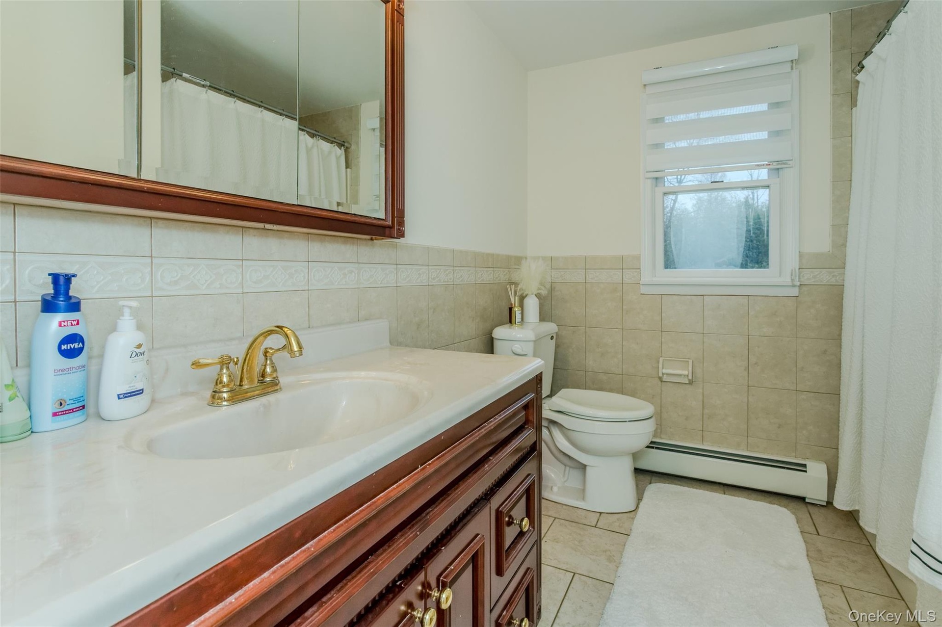 Bathroom with vanity, tile patterned flooring, toilet, baseboard heating, and tile walls