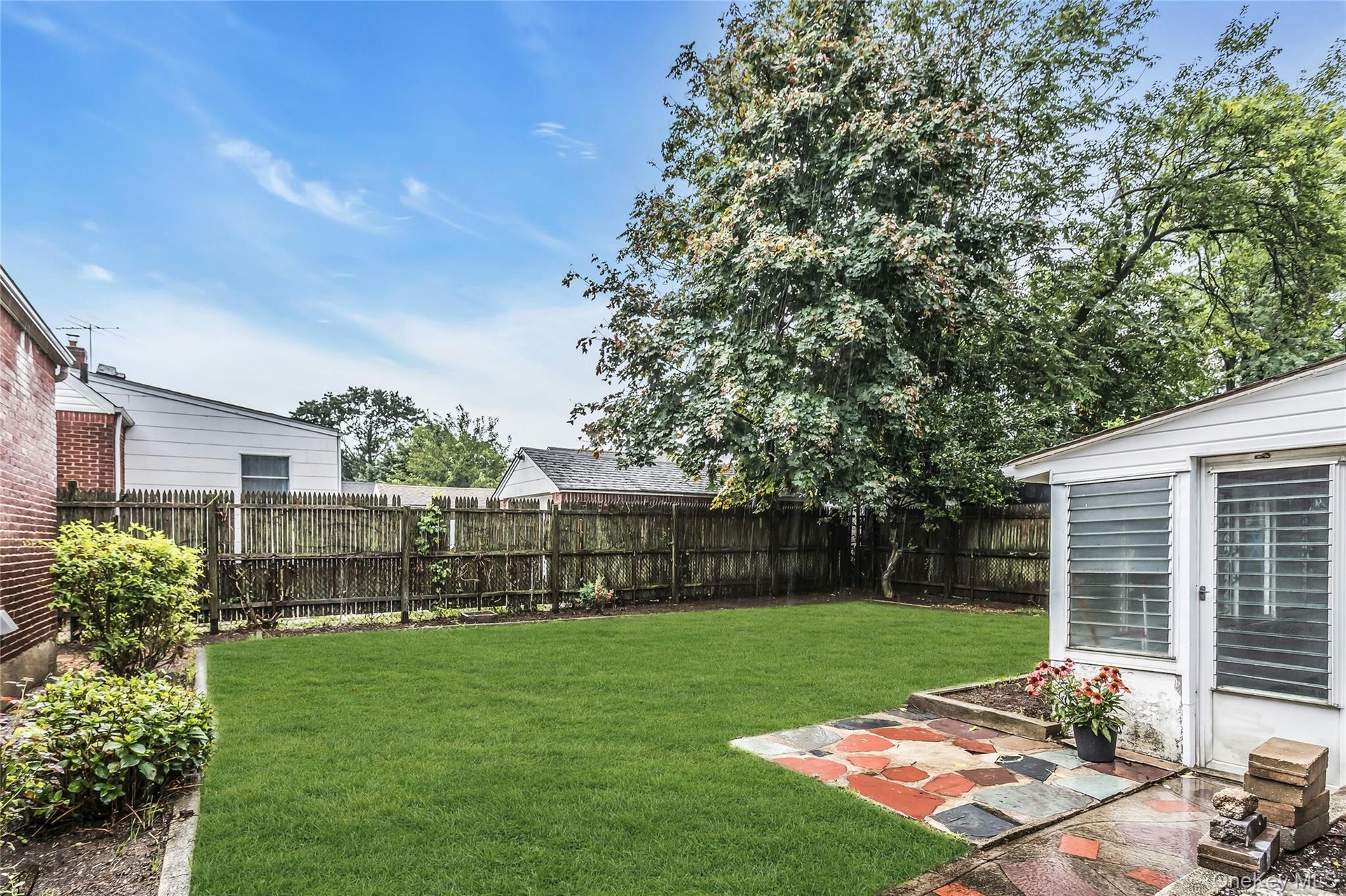 Expansive backyard featuring a manicured lawn, wood fencing, and mature trees  detached Garage and Greenhouse