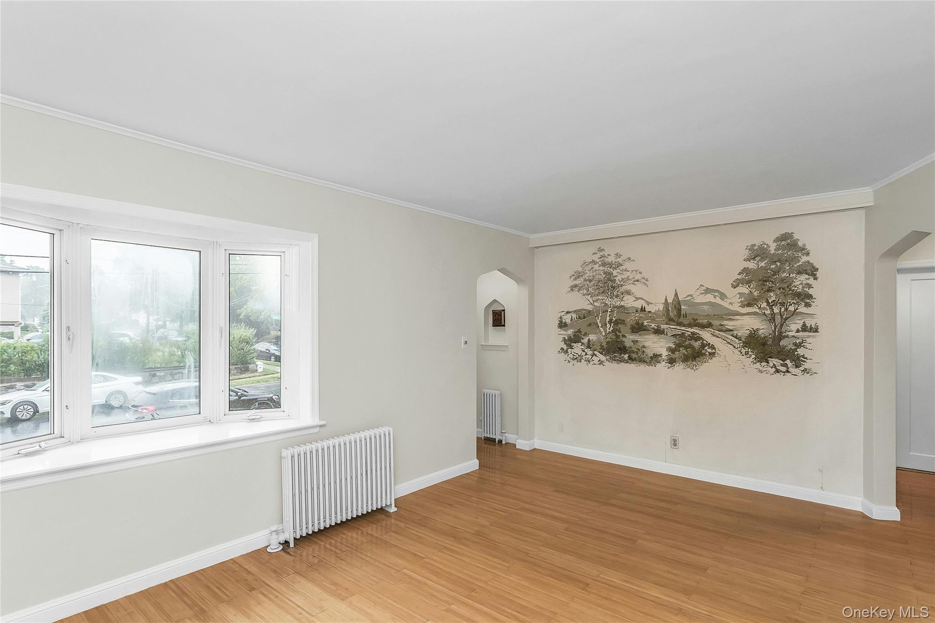 Bright interior space featuring a multi-pane bay window, wood-finish flooring, and a decorative wall mural