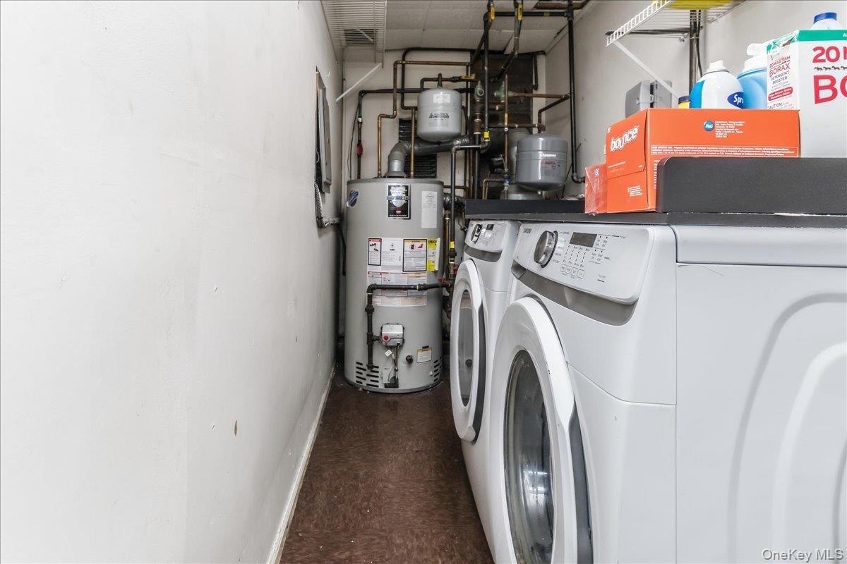 Utility area featuring a side-by-side washer and dryer, water heater, and exposed plumbing